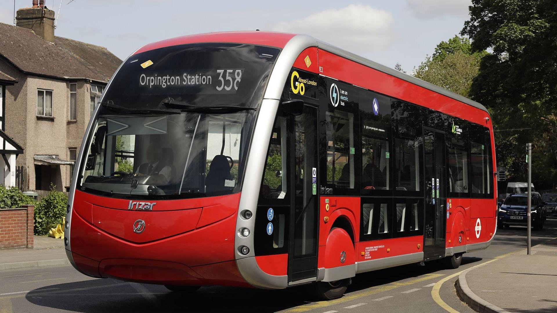 File image of one of the new 358 red single-decker buses, which have a slanted windscreen that curves under at the bonnet, and red hubcaps over the tyres. The pantograph arm is not visible