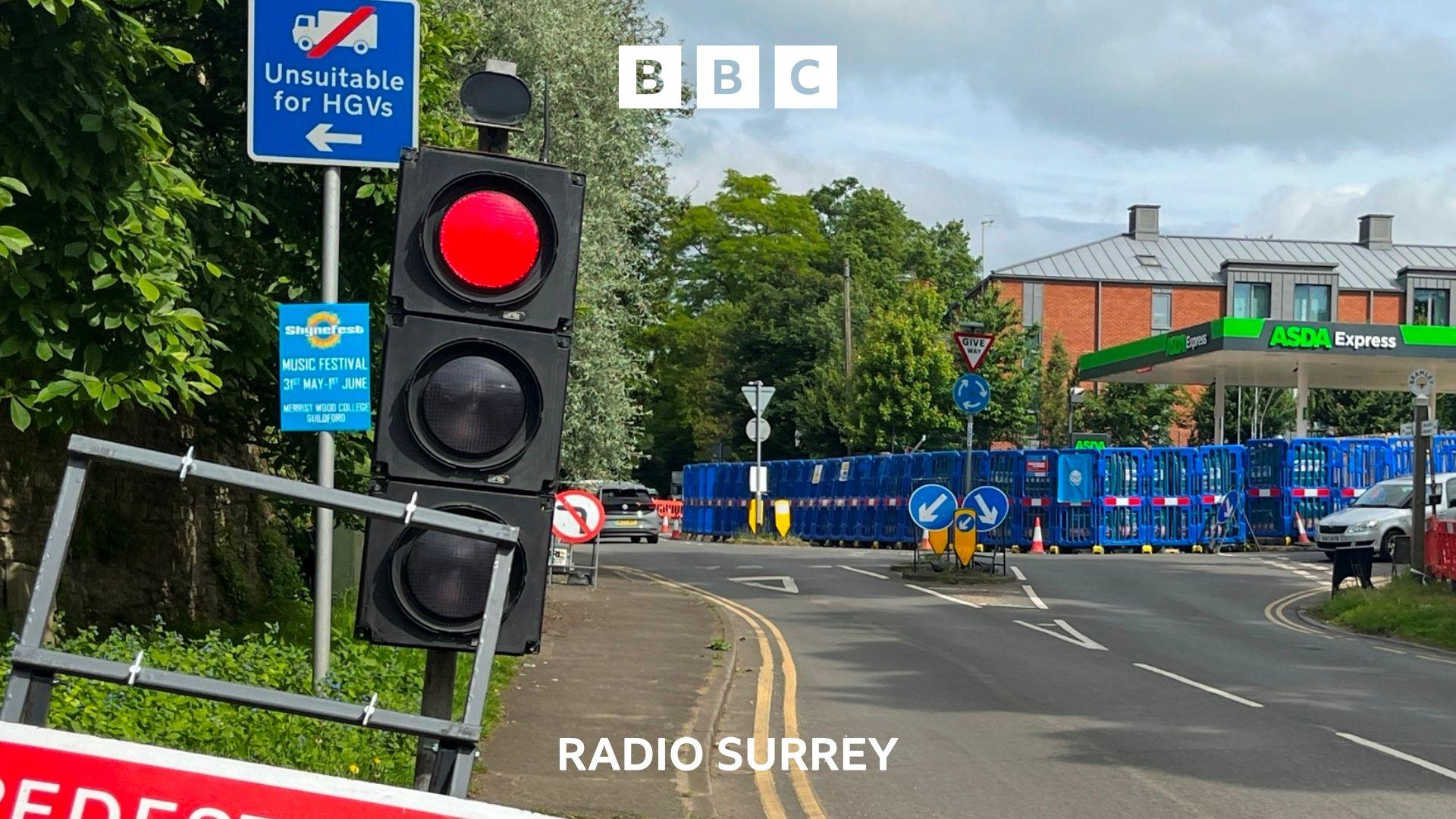 A temporary traffic light is shining red as roadworks around an Asda petrol station are ahead.