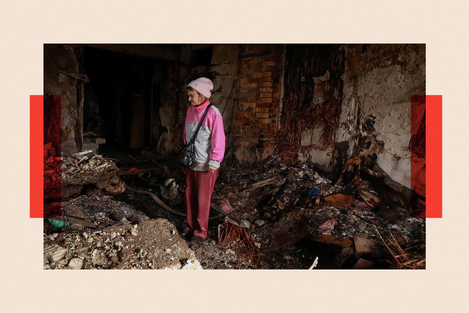 Një grua e veshur me rozë inspekton rrënojat pas një sulmi rus ndaj Ukrainës