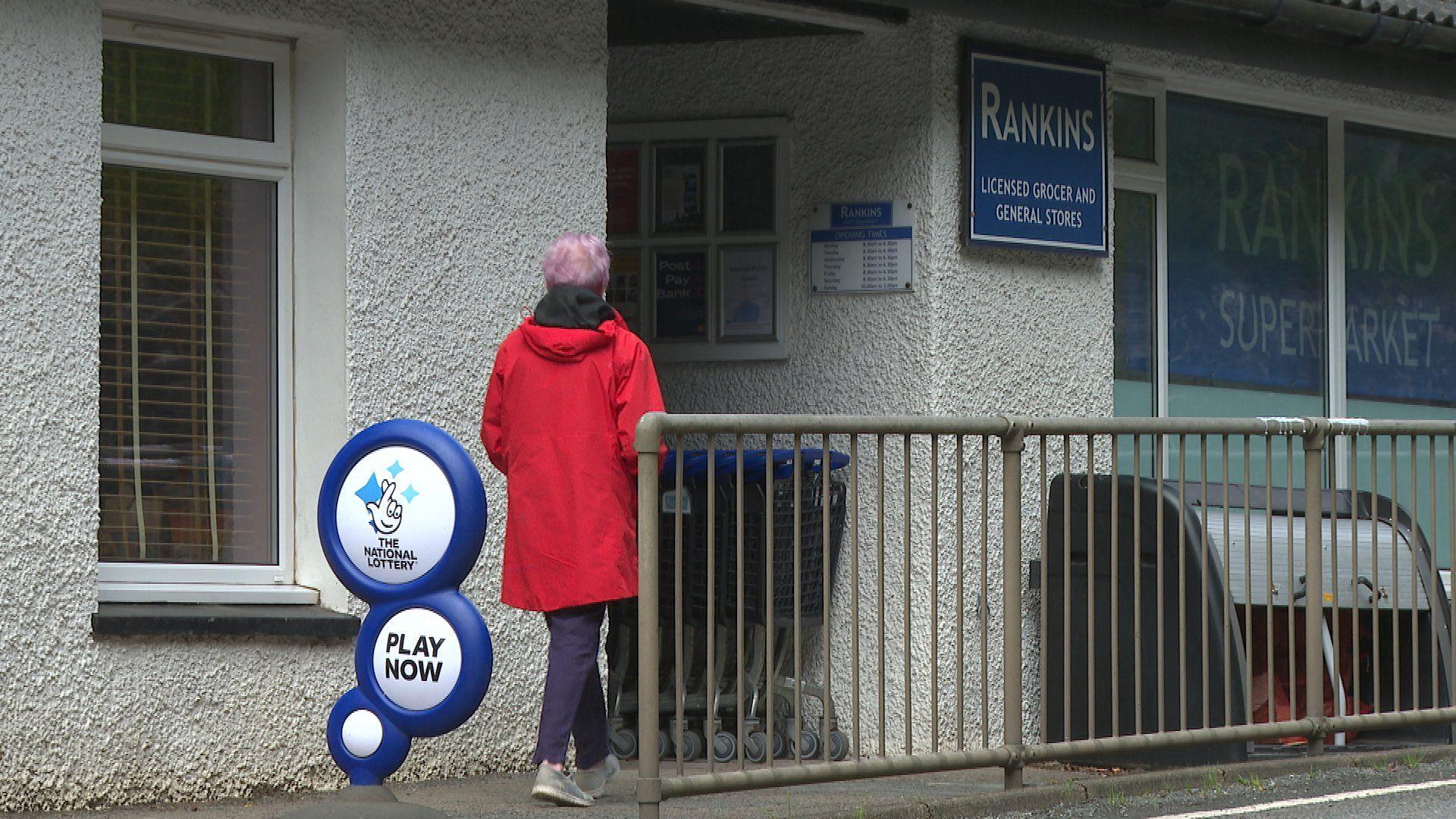 Boireannach a' coiseach a-steach a Bhùth Rankins ann an Ùige