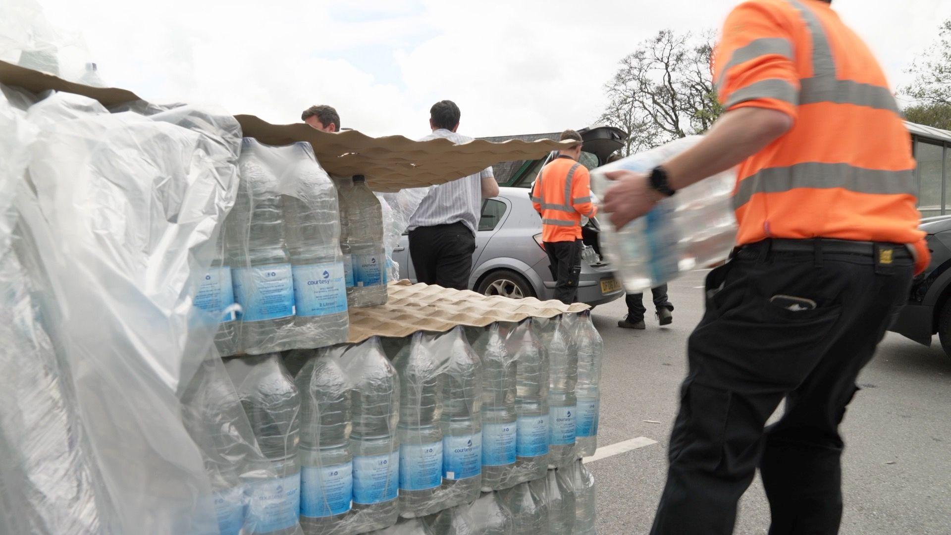Bottled water on the left and a man removing a crate from the stack.