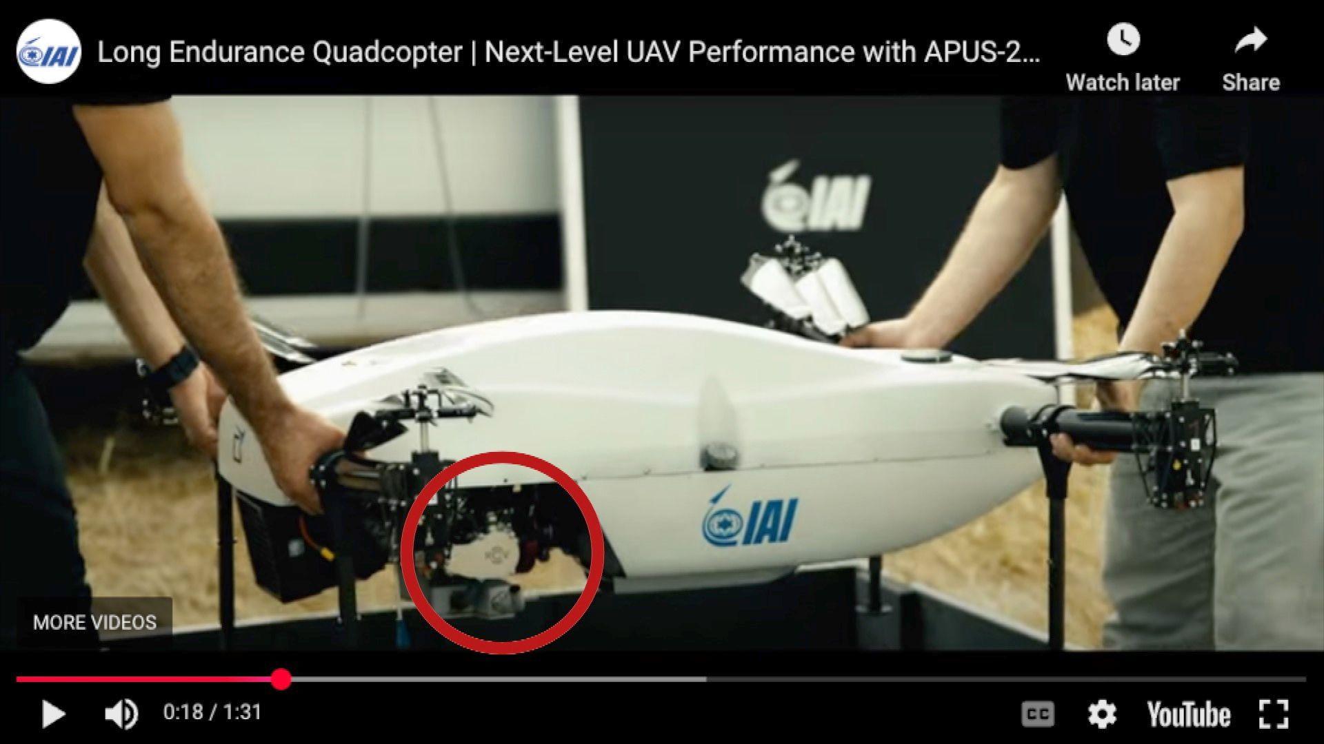 A screenshot of a Youtube video paused showing two people holding a white drone with a logo circled in red