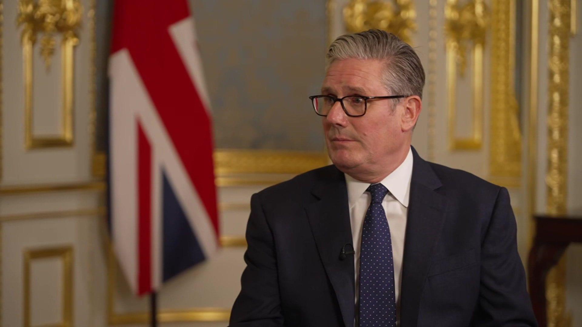 SIr Keir Starmer sits in an ornate room with a Union Jack in the background