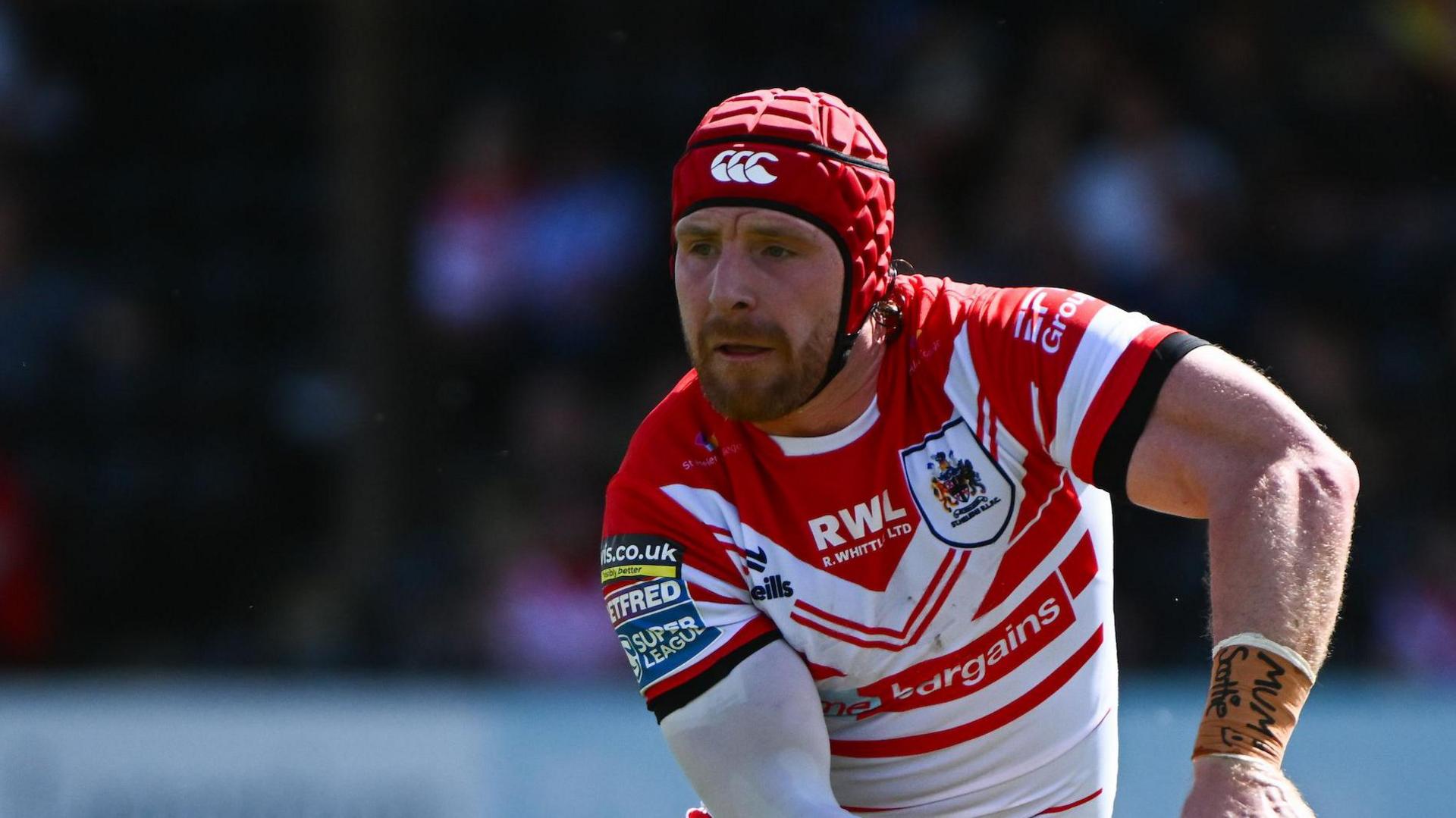 St Helens player Jackson Hastings about to pass the ball with his left hand. He is wearing a scrum cap.