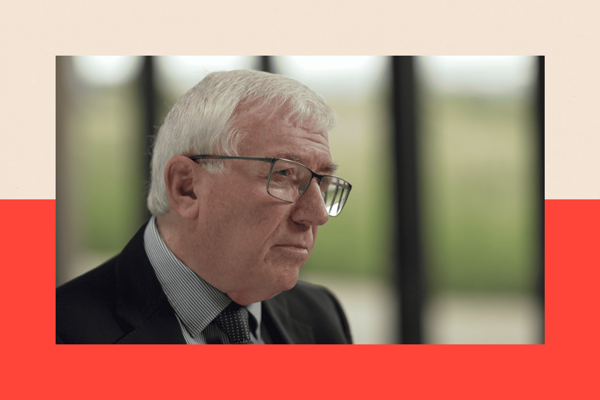 Dr Mike Hall wears glasses and a suit, and looks away from the camera