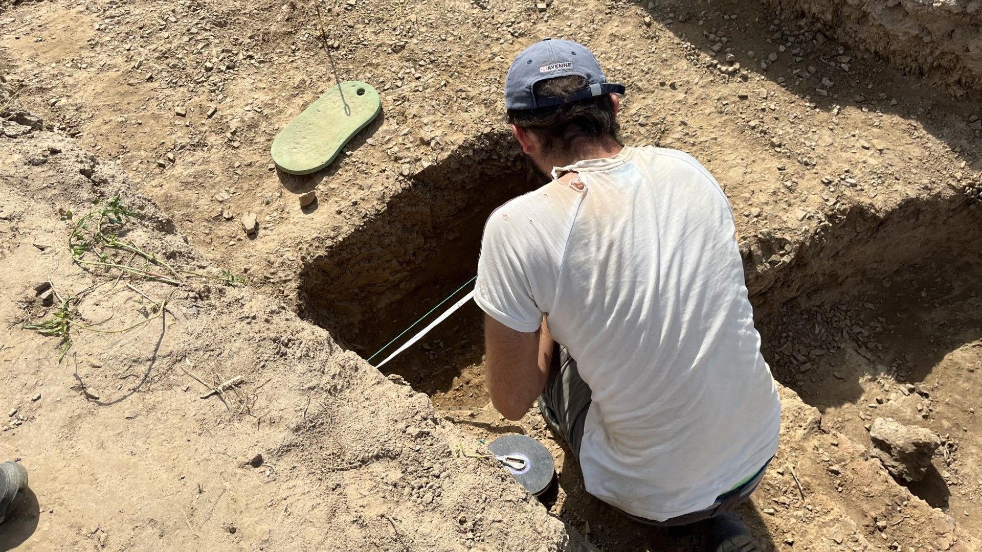 Man digging in trench as part of archaeological dig