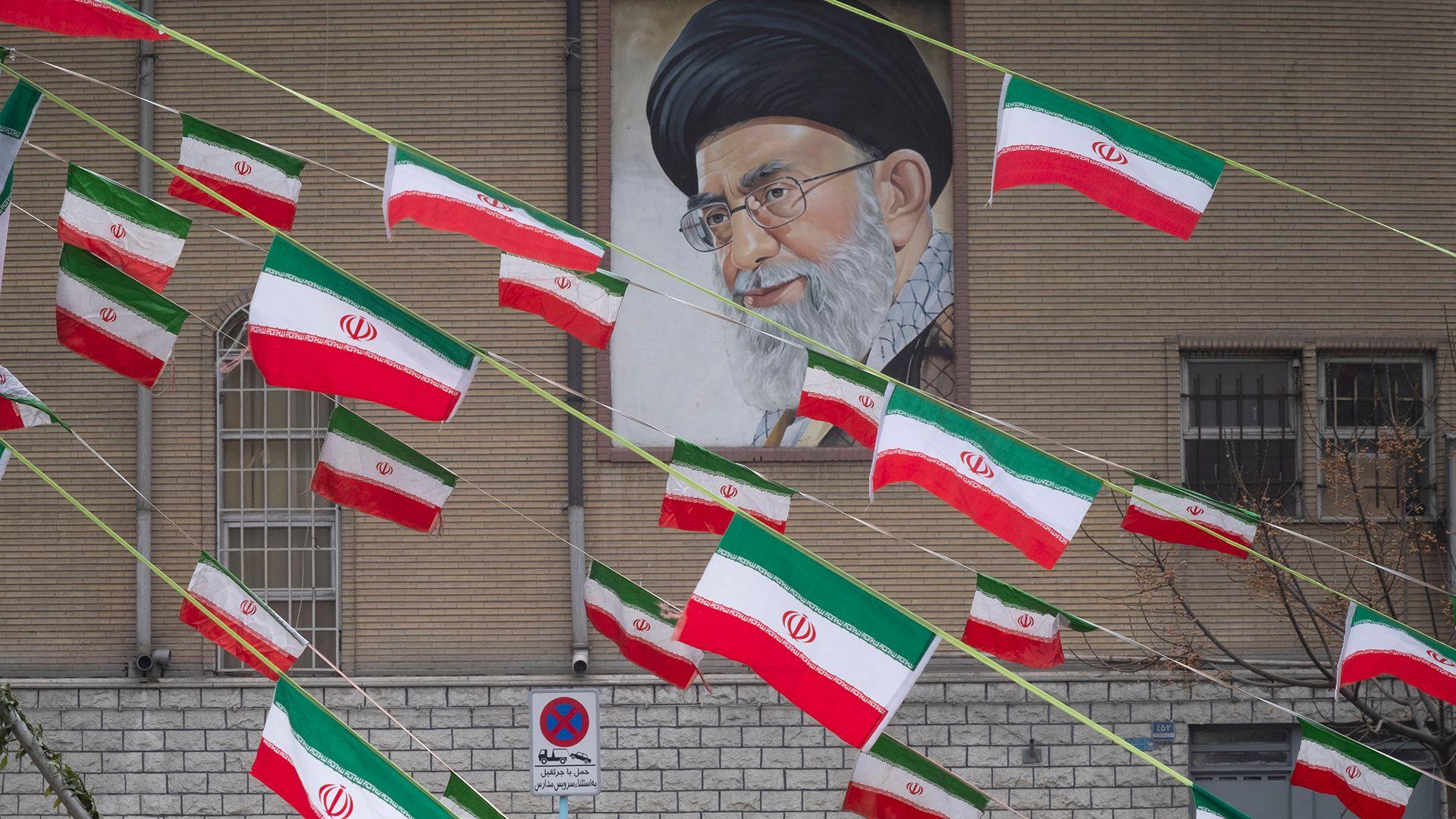 A mural of Iran's Supreme Leader Ayatollah Ali Khamenei is seen on the side of a building in Azadi avenue with reams of Iranian national flags hanging in the foreground, in Tehran on 11 February 2022.