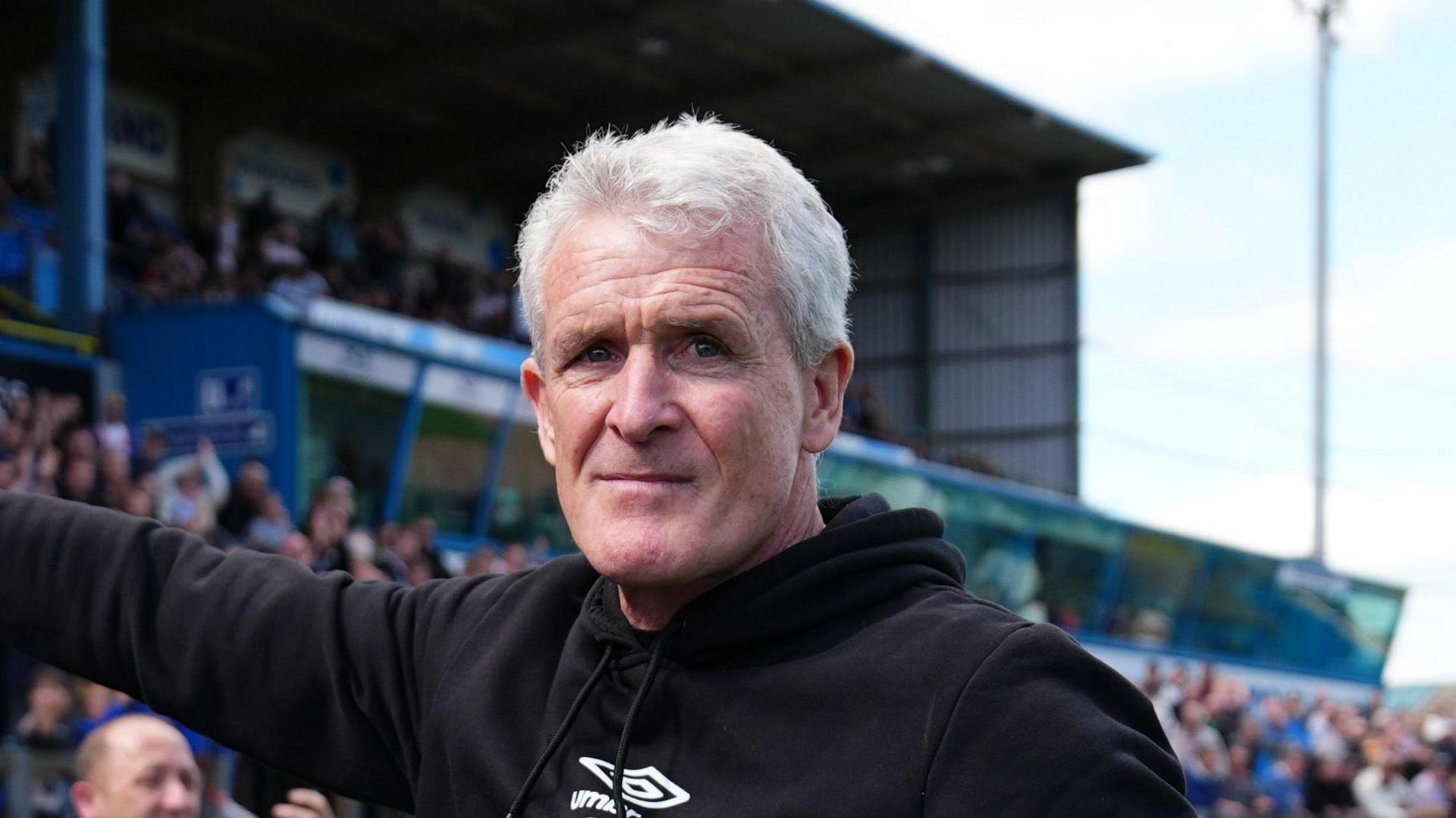 Mark Hughes, wearing a black tracksuit, pictured at Brunton Park