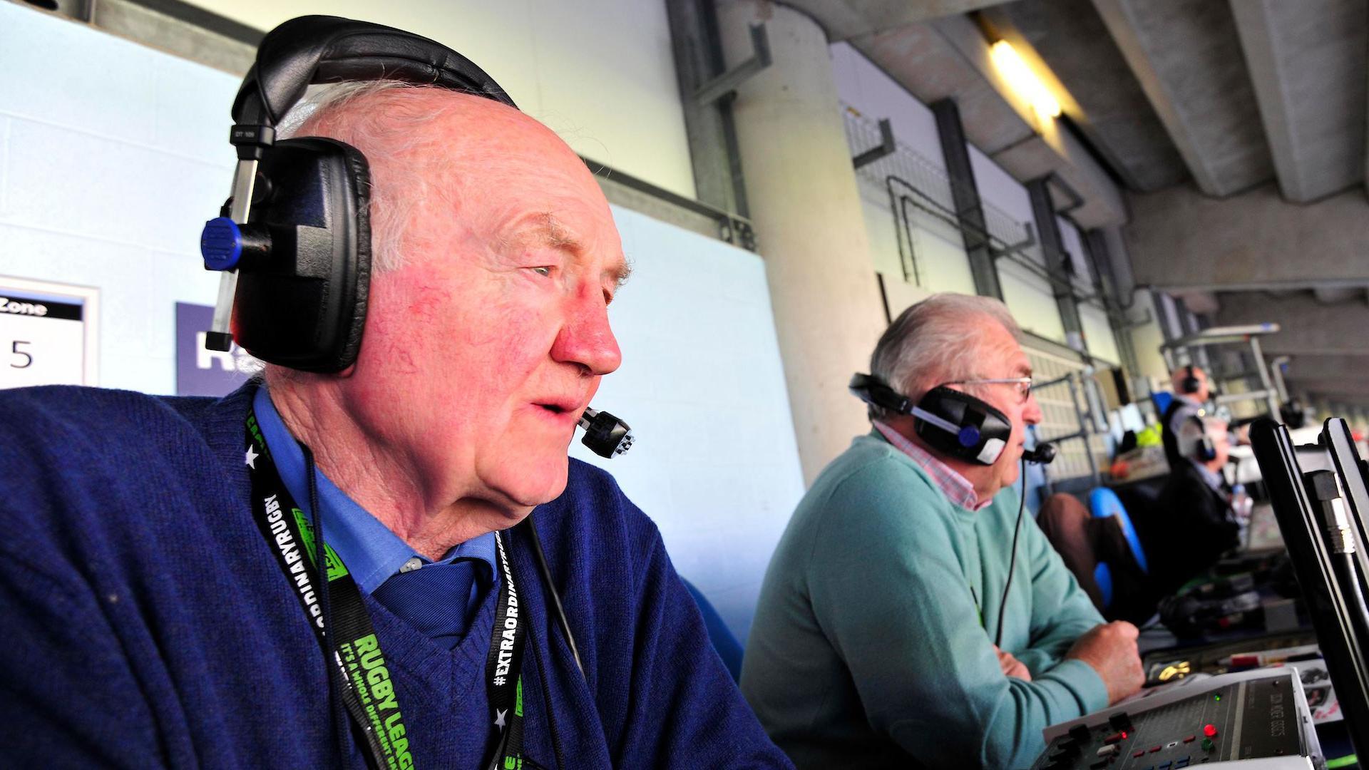 Ray French with headset-microphone on sits next to colleague Allan Rooney in the press box at Manchester City's Etihad Stadium while commentating on a match for BBC local radio.
