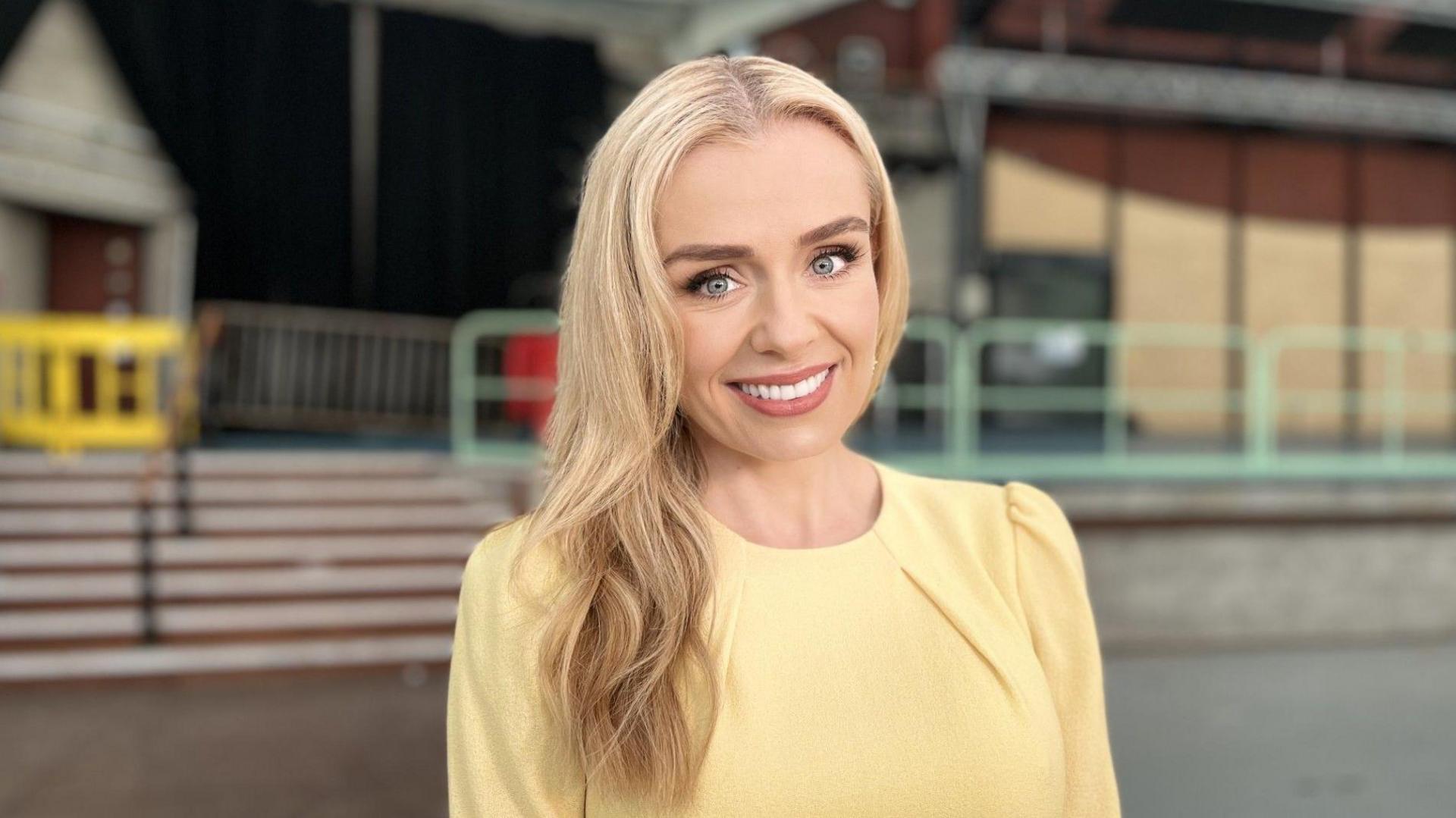 Singer Katherine Jenkins smiling, wearing a yellow dress