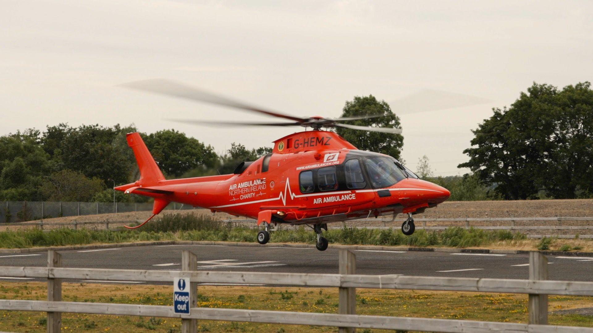 An Air Ambulance helicopter hovering above the ground with the rotor blades blurry from spinning fast