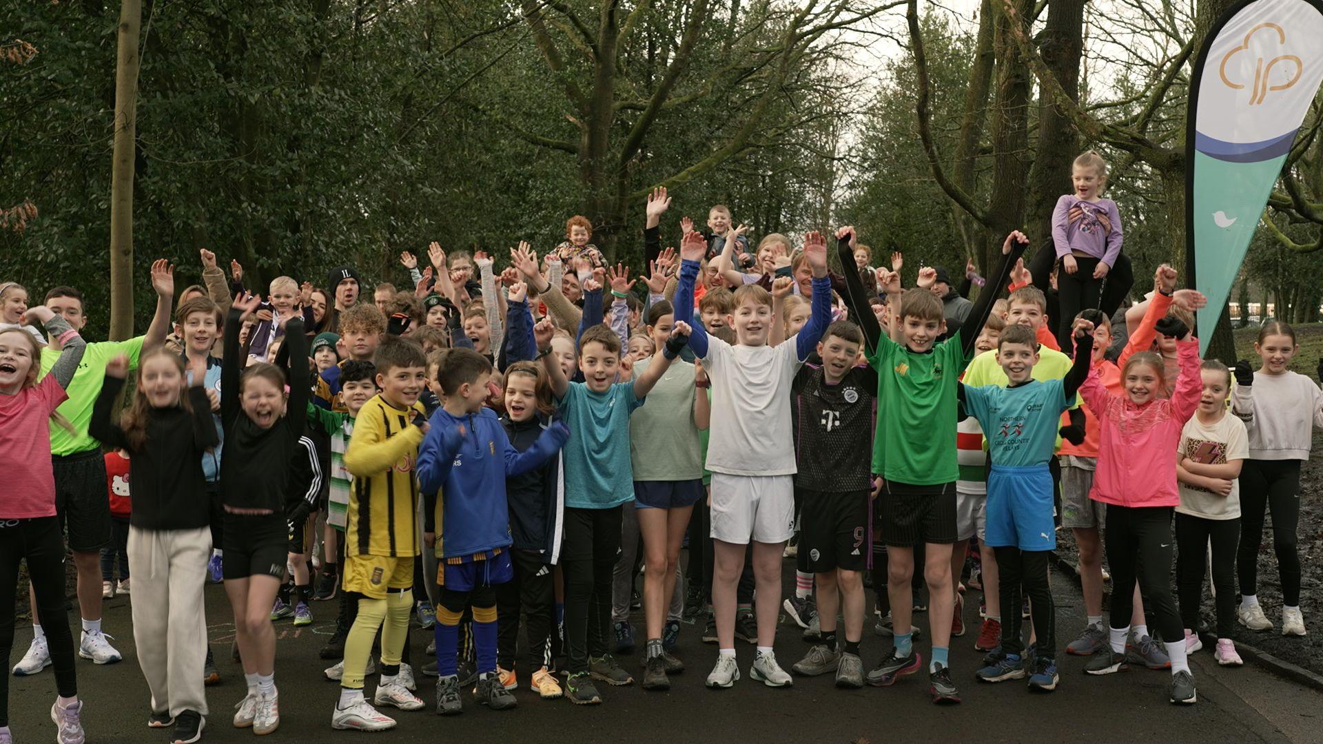 A group of children stand with their hands in the air cheering