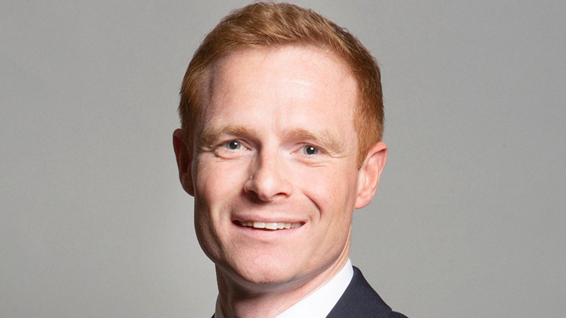 A man with short ginger hair wearing a suit