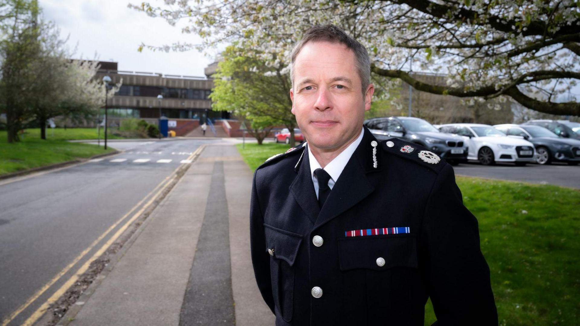 Paul Gibson with short dark hair wearing a police uniform outside police headquarters