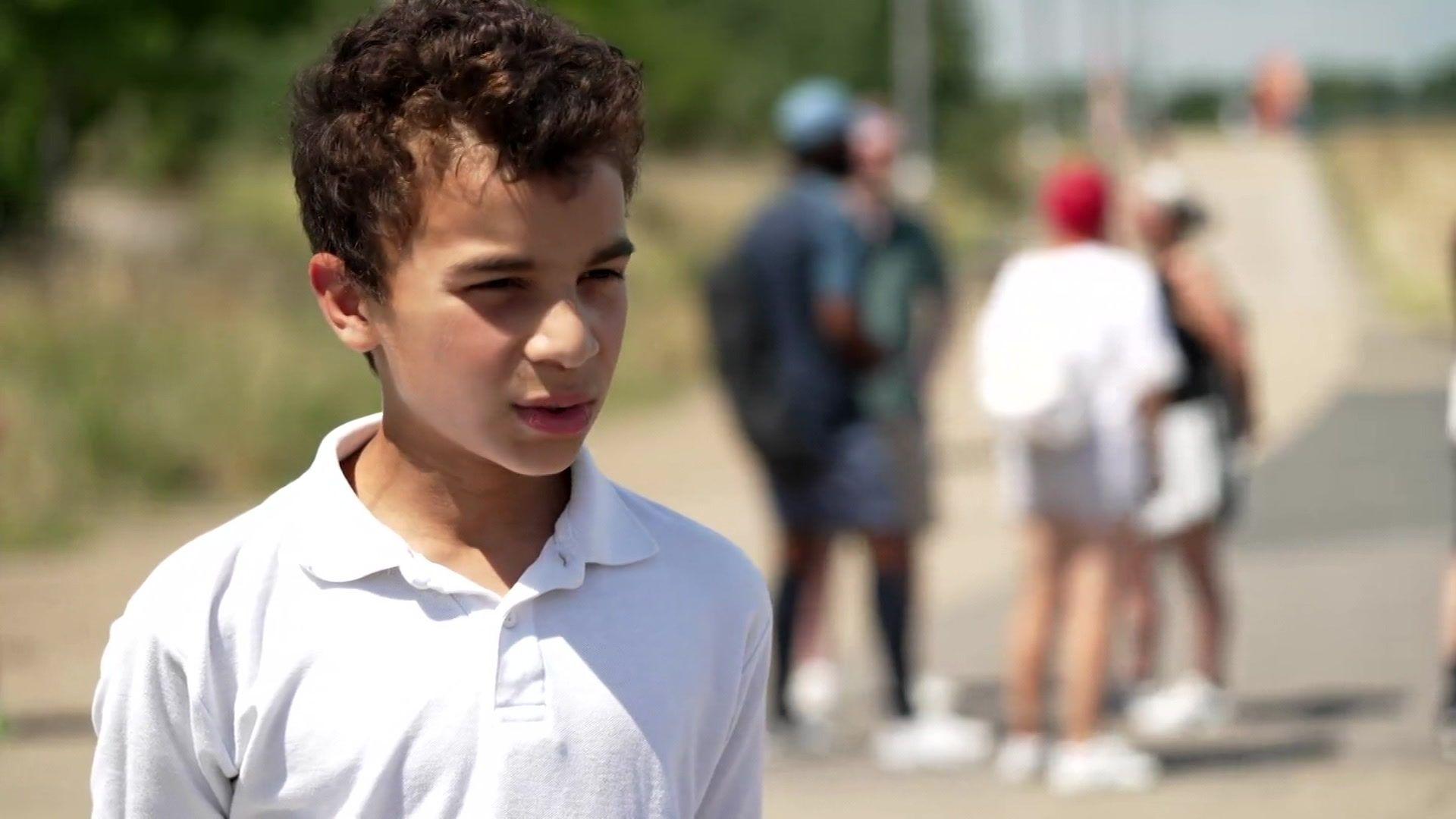Isaac, aged eight, a boy with dark hair, wearing a white tennis shirt