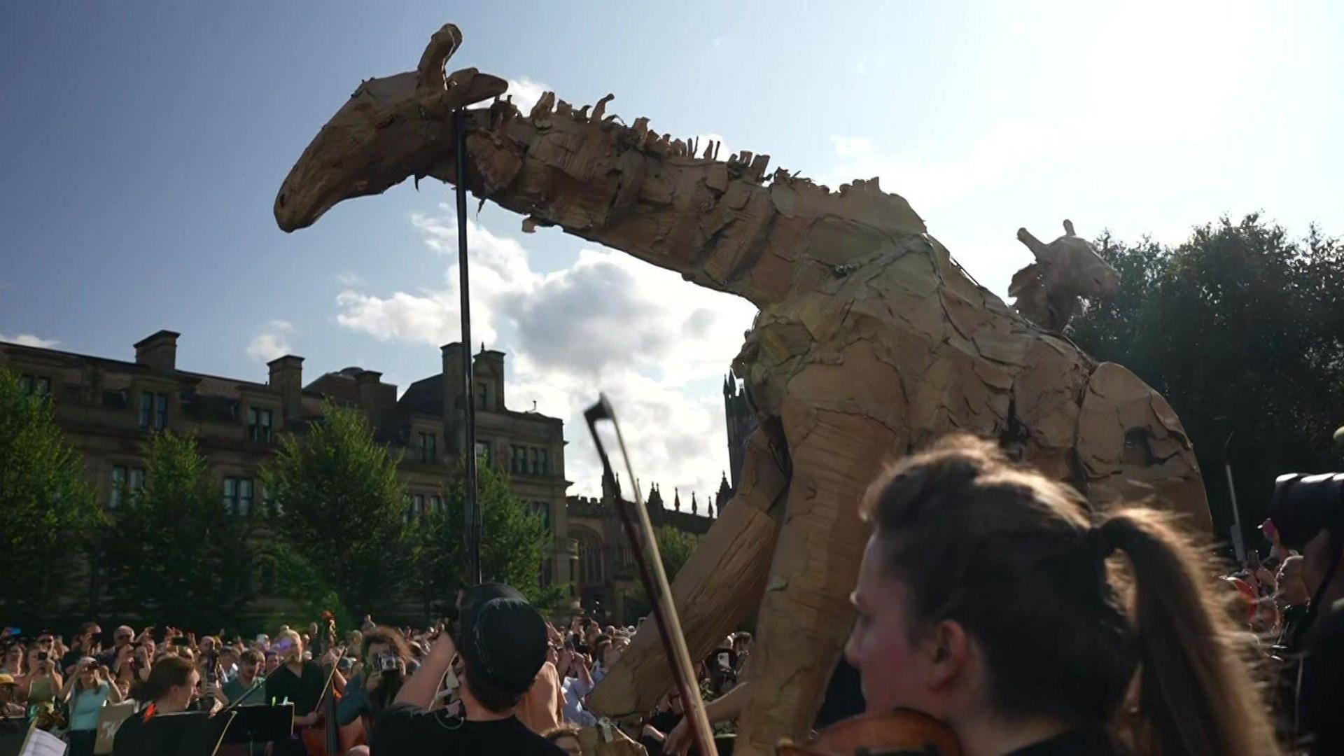 Woman plays violin next to a wooden giraffe