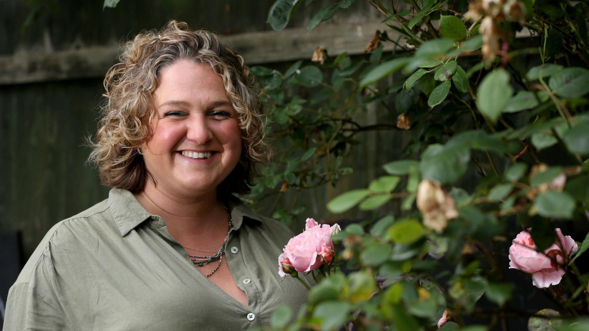 Cancer patient Anoushka Duroe-Richards smiles standing in a flower garden.