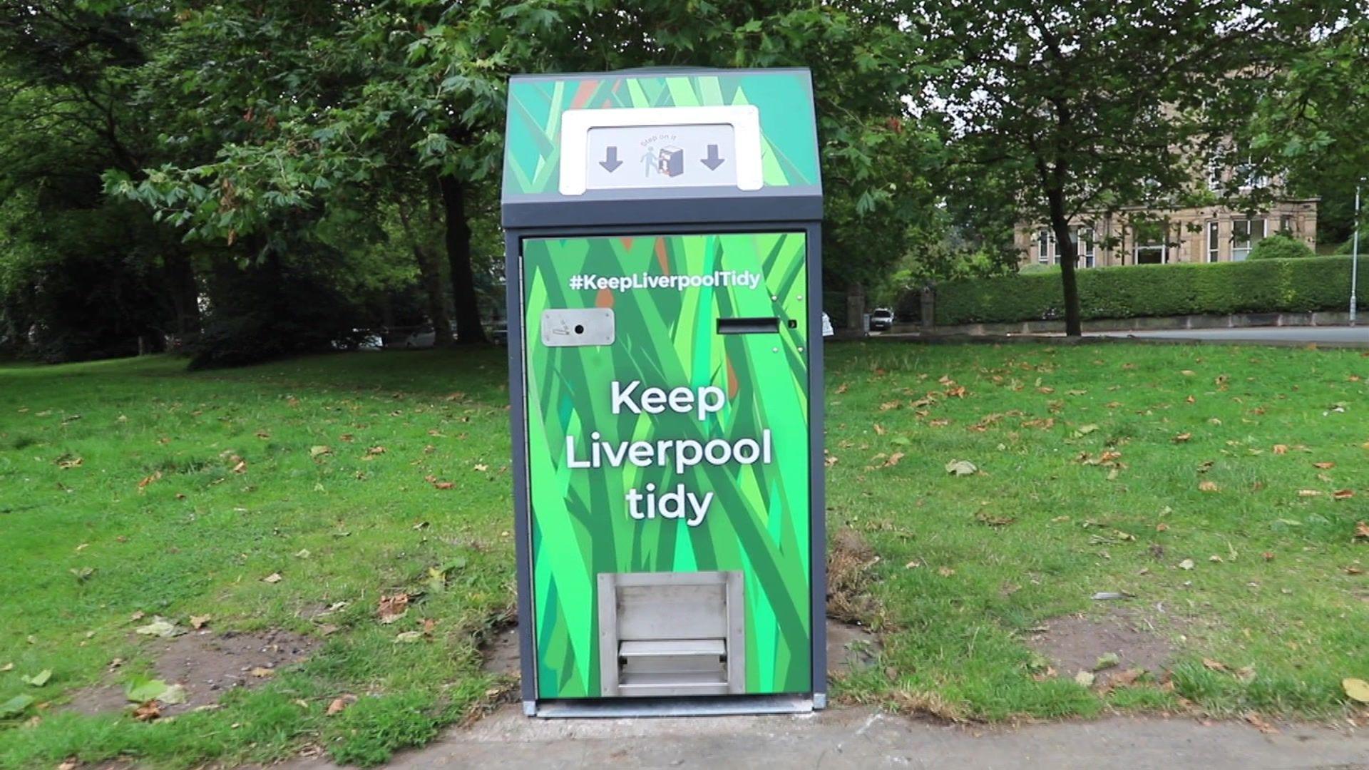 A green bin in a park with "keep Liverpool tidy" written on it