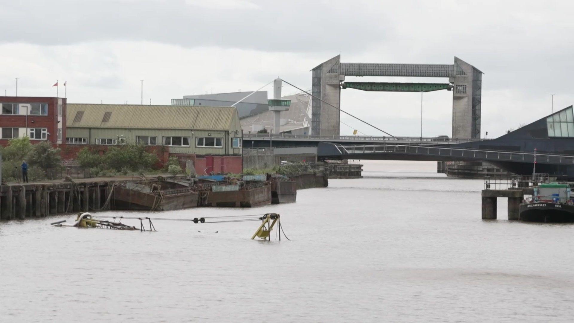 A view of the River Hull looking towards the city's tidal barrier. The top of a crane barge is just visible through the surface of the water.
