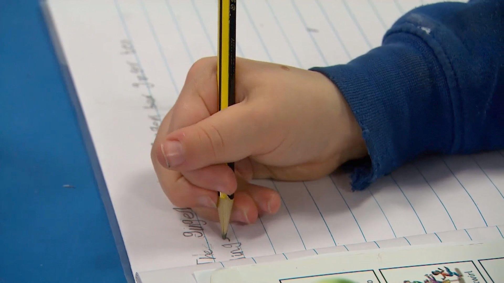 A child's hand writing in a school exercise book.