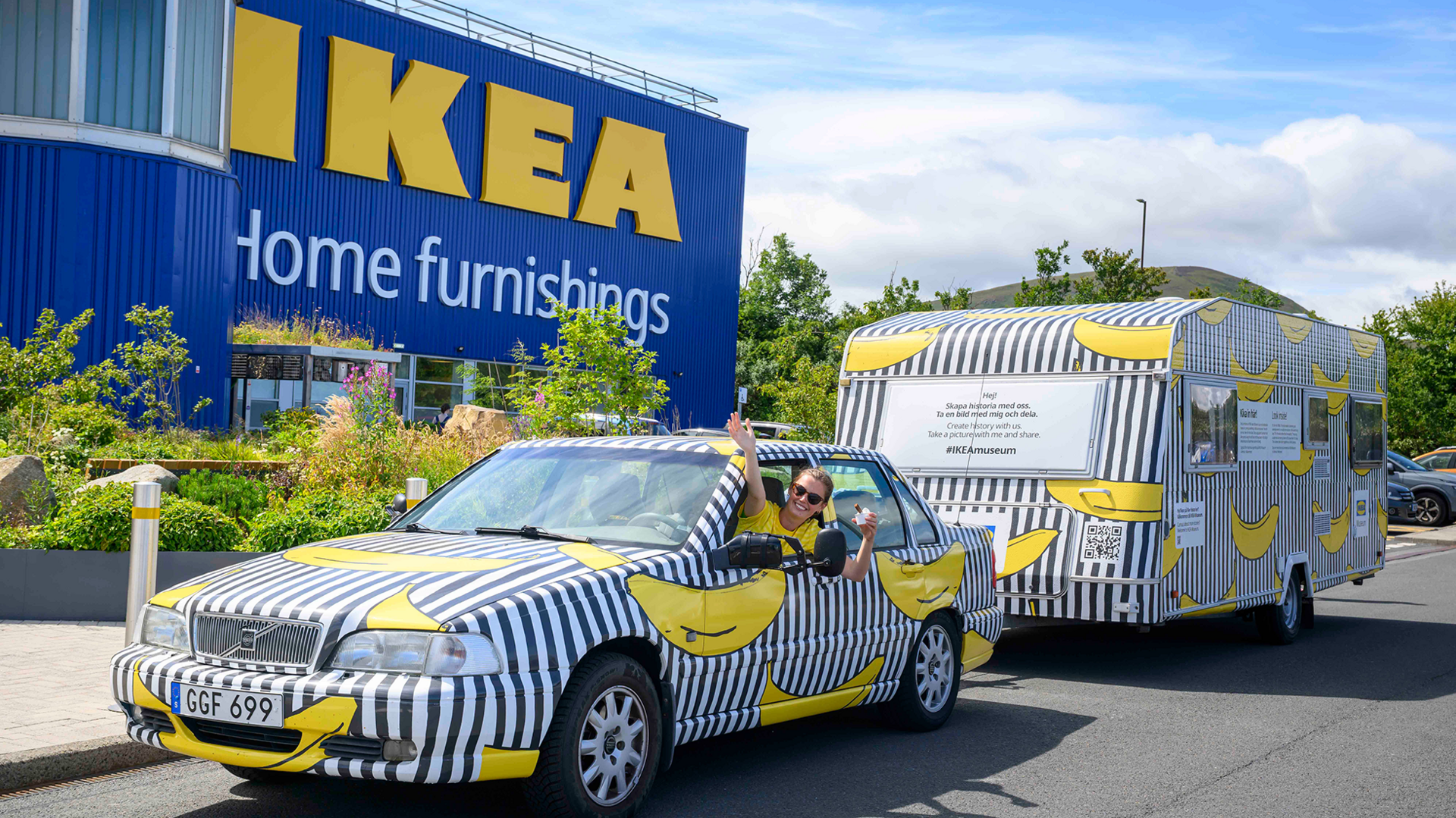 A Volvo car - wrapped in the famous banana design - pulls a caravan covered in the same design outside an Ikea store