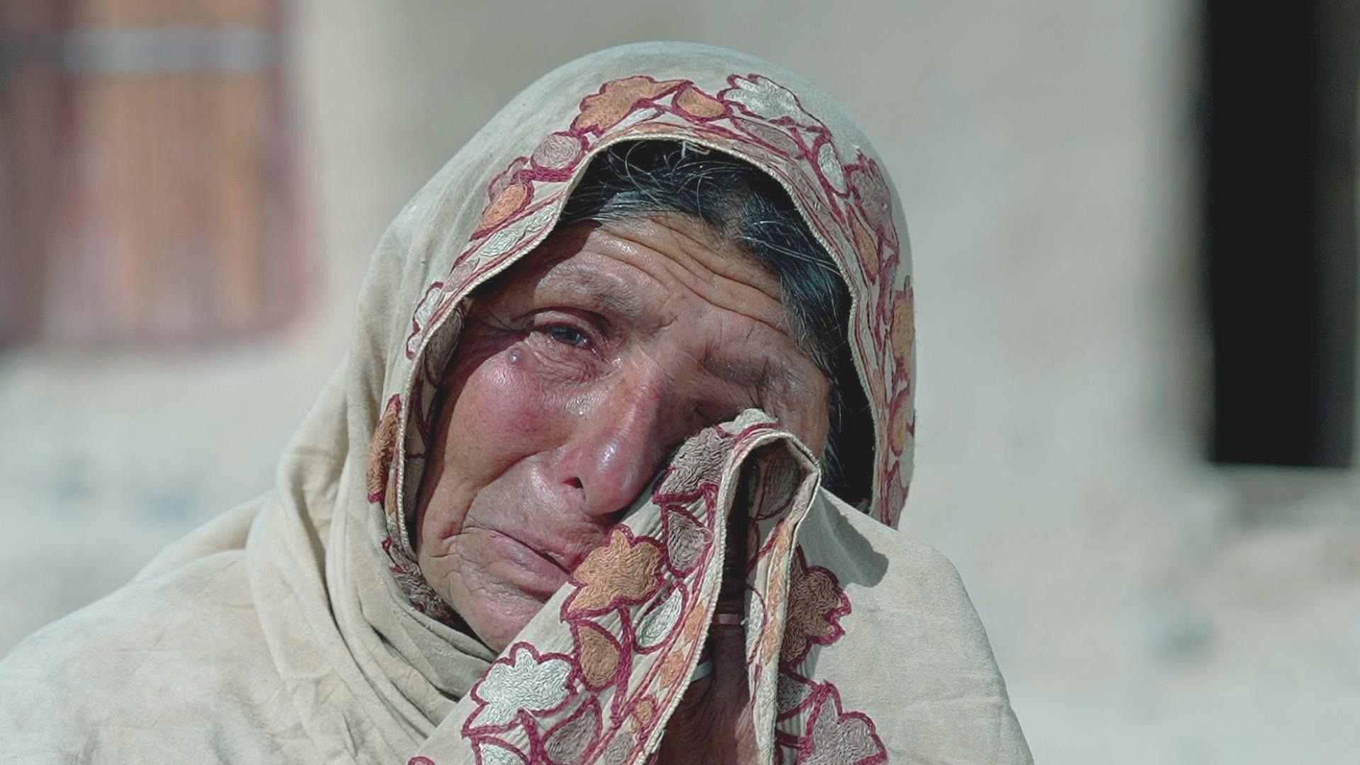 An older lady in a headscarf cries