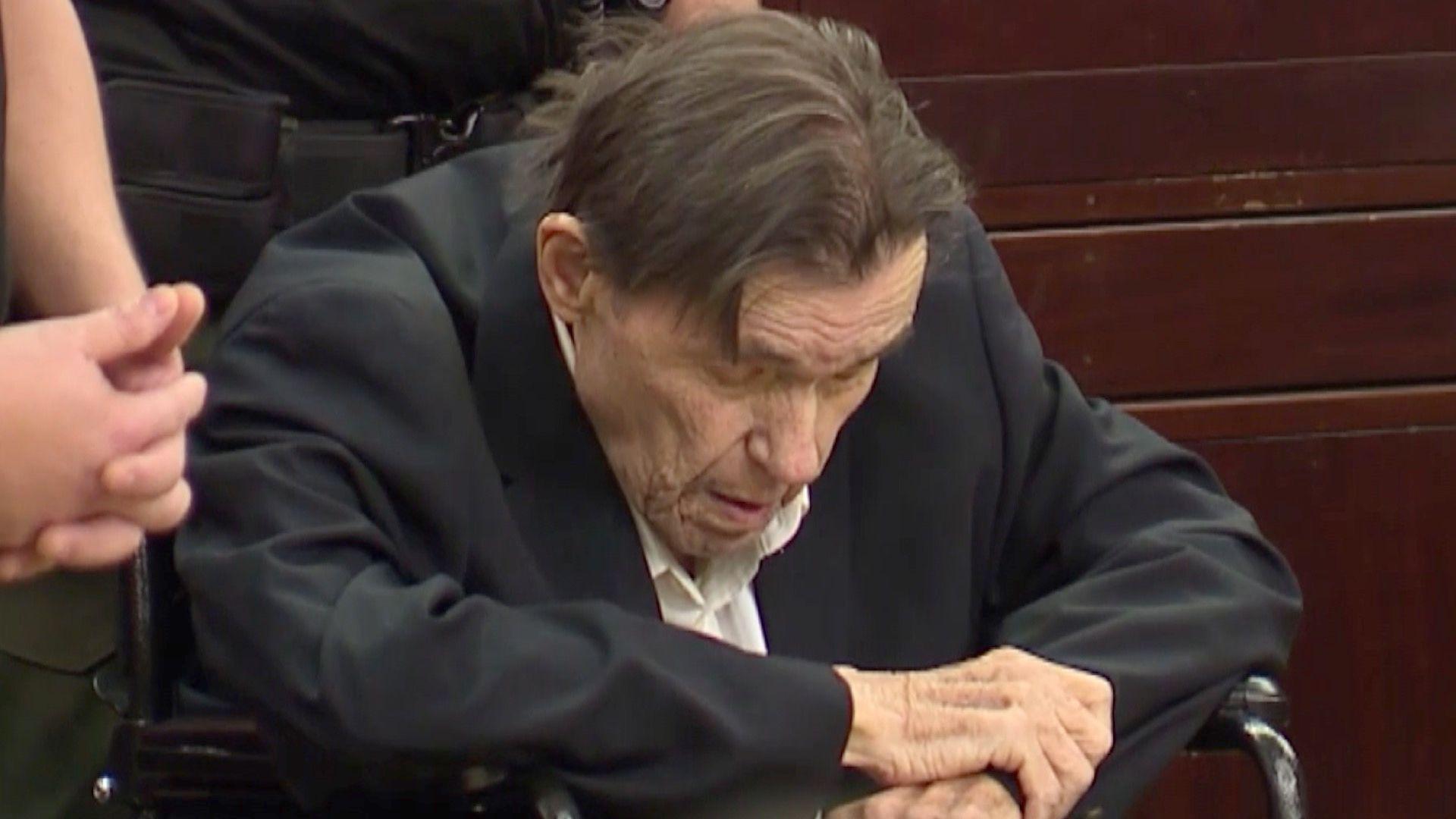 Andrew Lester is seated in court in a wheelchair, it a dark suit coat and white shirt with his head bowed so his expression can't be fully seen 