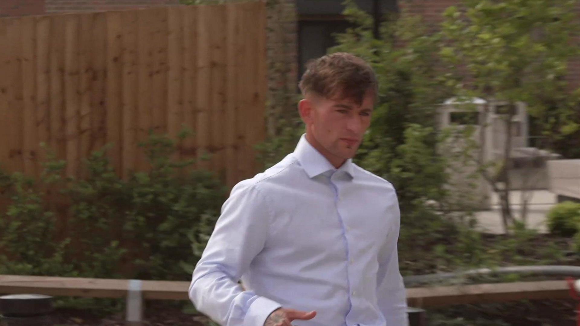 Kian Monks, who has short dark hair and is wearing a white shirt, is walking towards the court building.