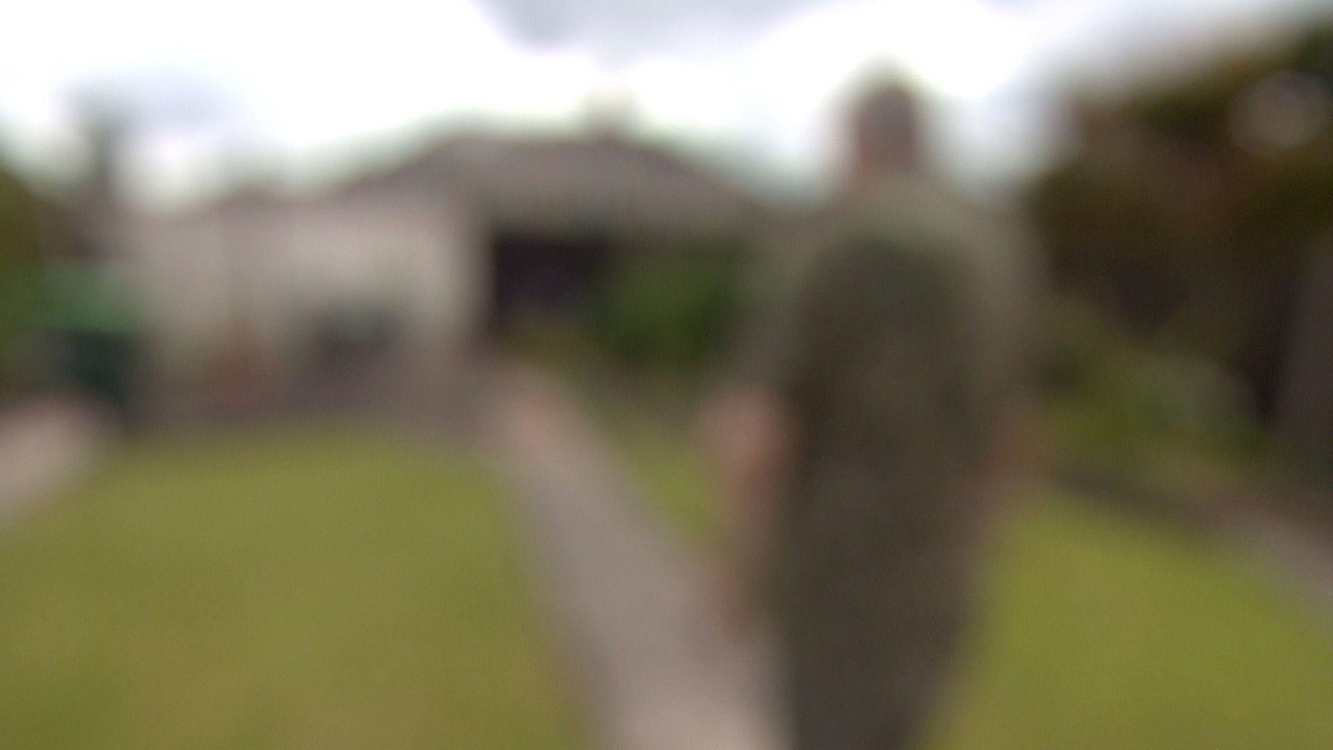 Blurred image of a man walking down a garden path