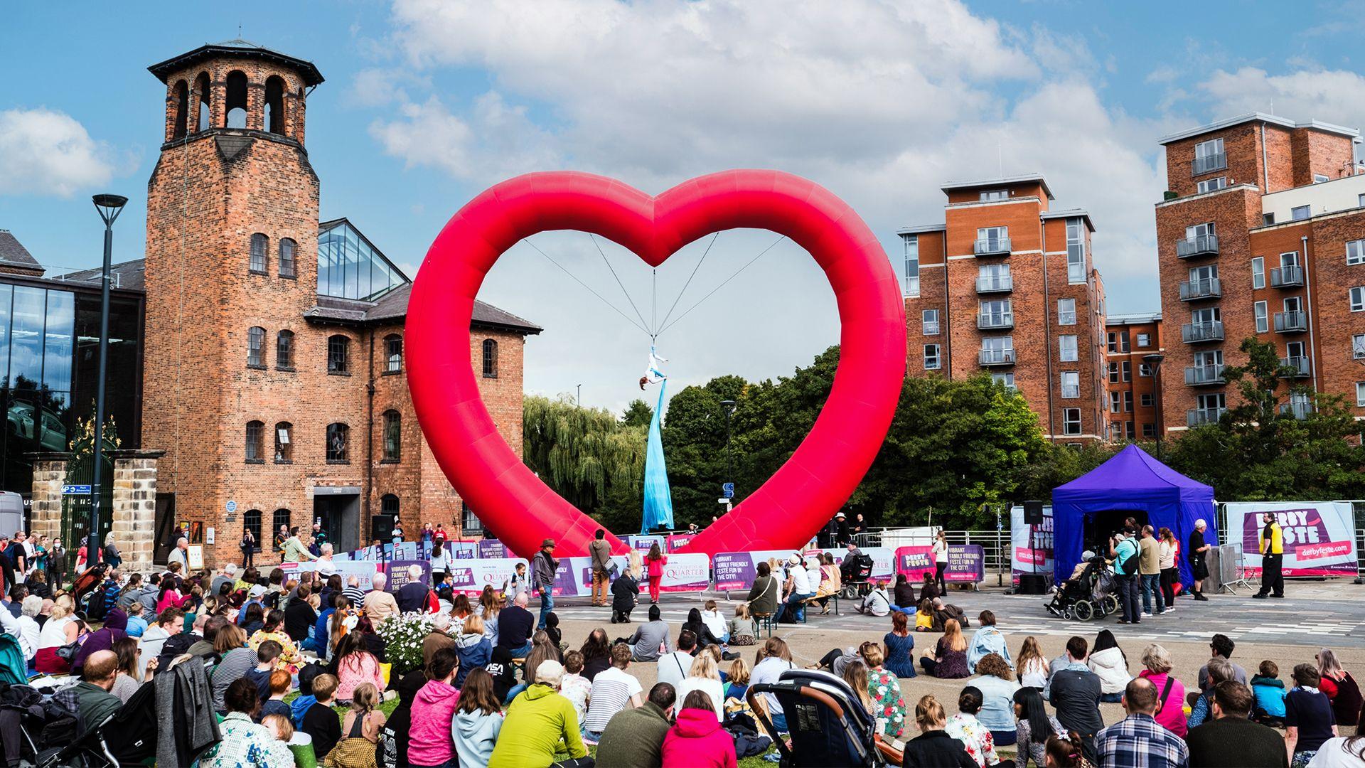 A dancer performing inside a large heart in Derby city centre
