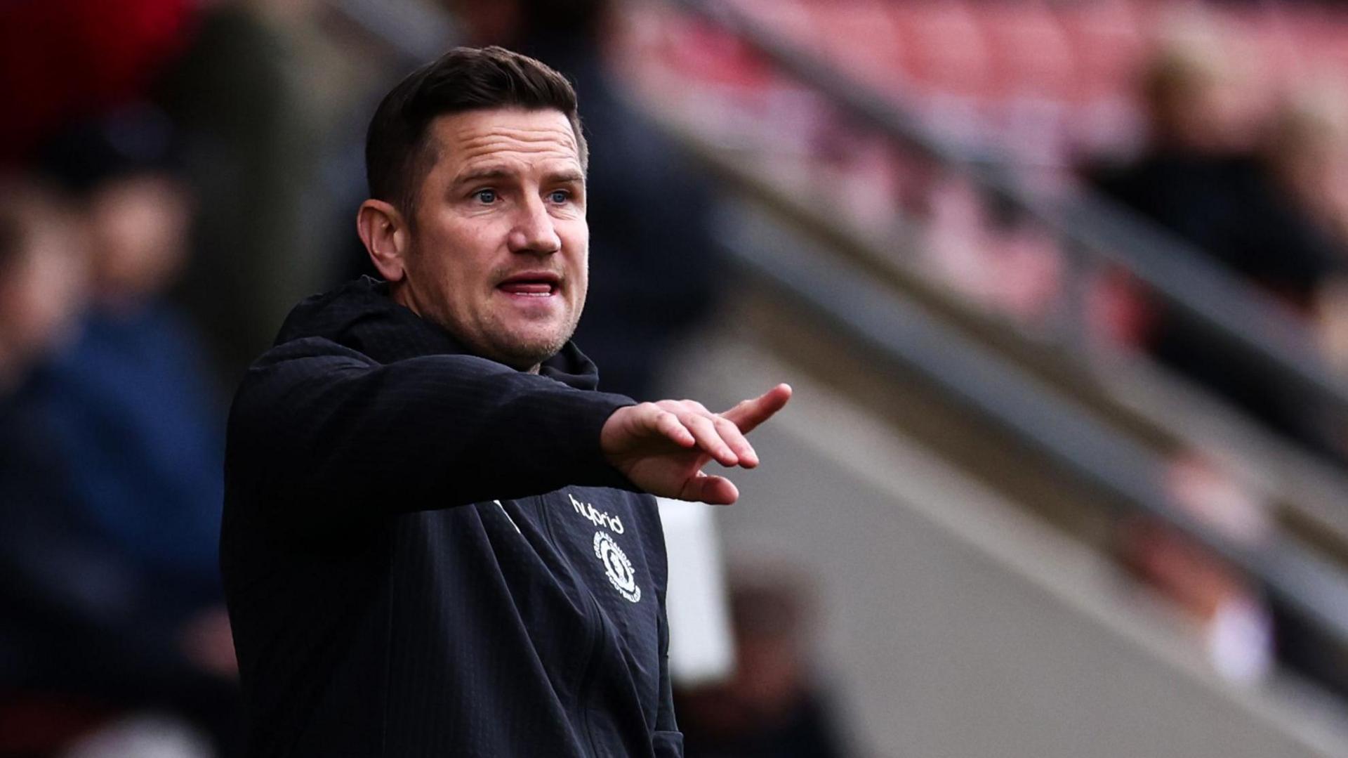 Crewe boss Lee Bell points from the dugout during a match