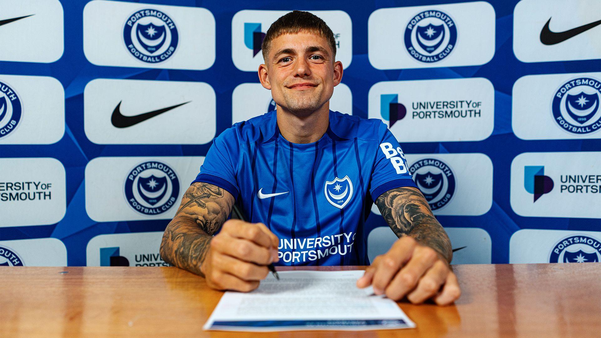 Danish striker Elias Sorensen sat at a desk prepares to sign his three-year contract after agreeing to join Portsmouth FC