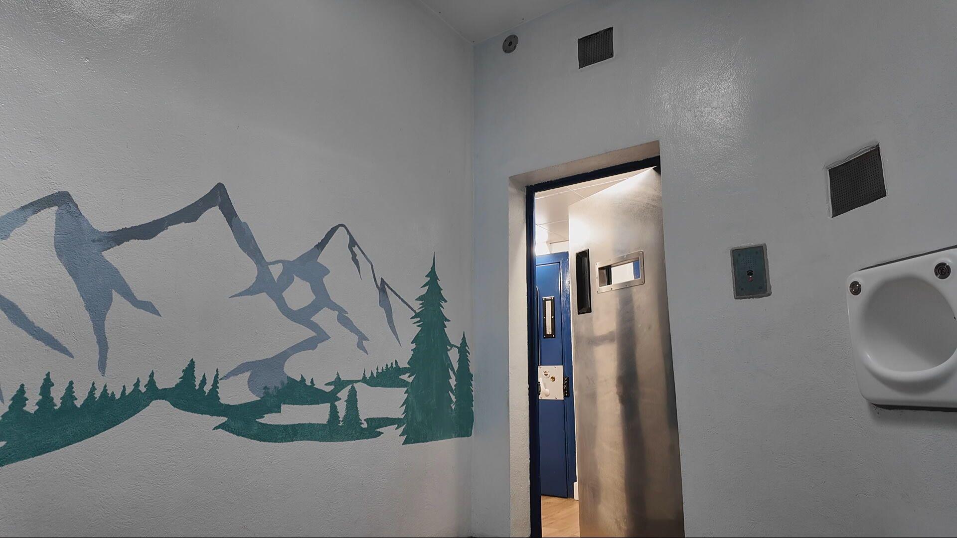 A cell with a mural on the wall of a mountain scene