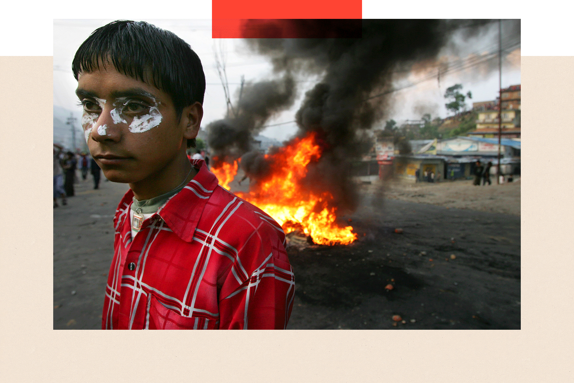 A Nepalese protester with toothpaste on his face used to counter act tear gas stands by a fire during demonstrations against the Monarchy of King Gyanedra path 