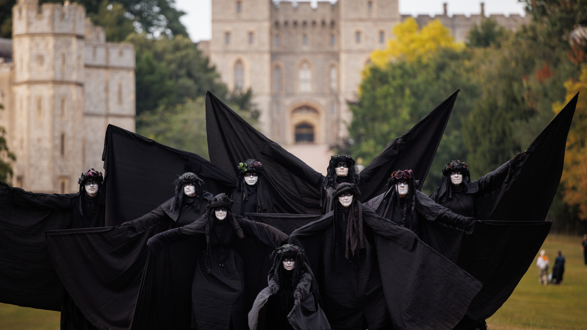 Nine Extinction Rebellion activists, wearing black and white face make-up, unfurl their black capes in Windsor Great Park.