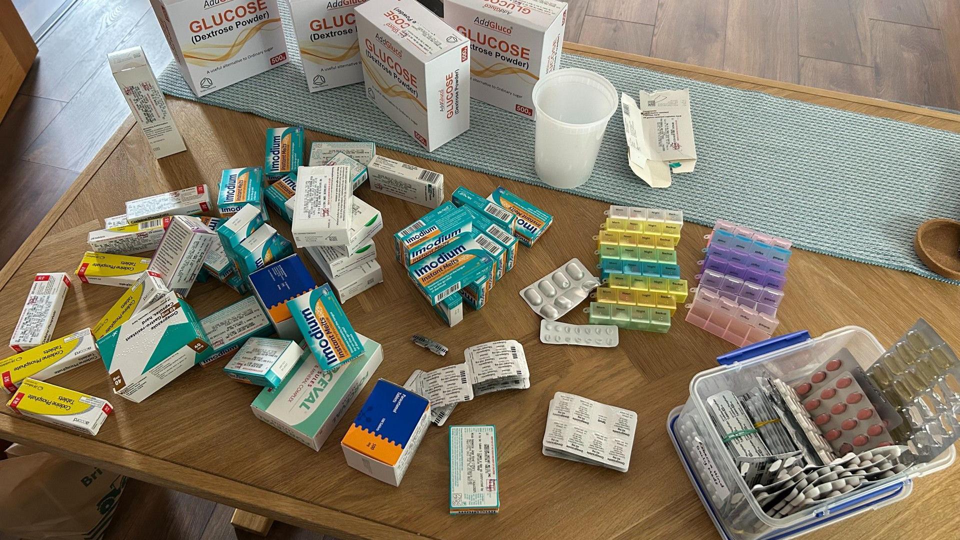 Lots of different types of drugs are laid on a table. These are the drugs that Bex said she had to consume to live with PMP.