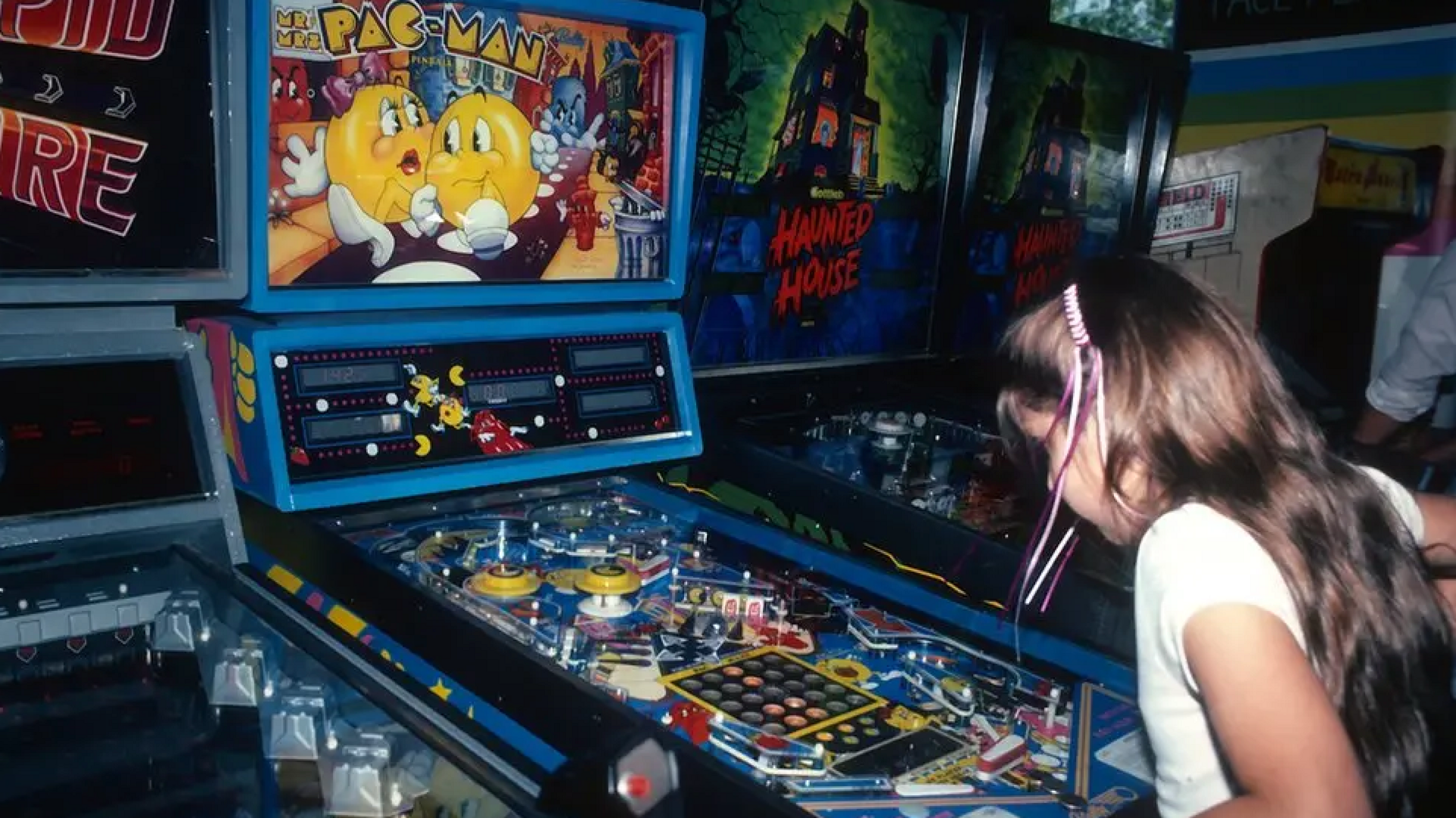 young girl playing pac man at arcade