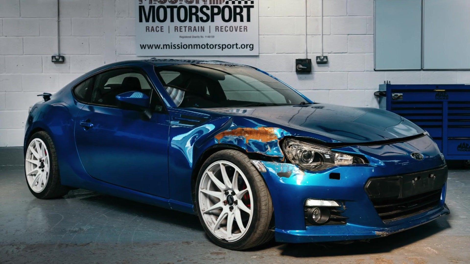 A blue 2016 Subaru BRZ in the Mission Motorsport workshop. The front right of the car is crumpled following a crash.