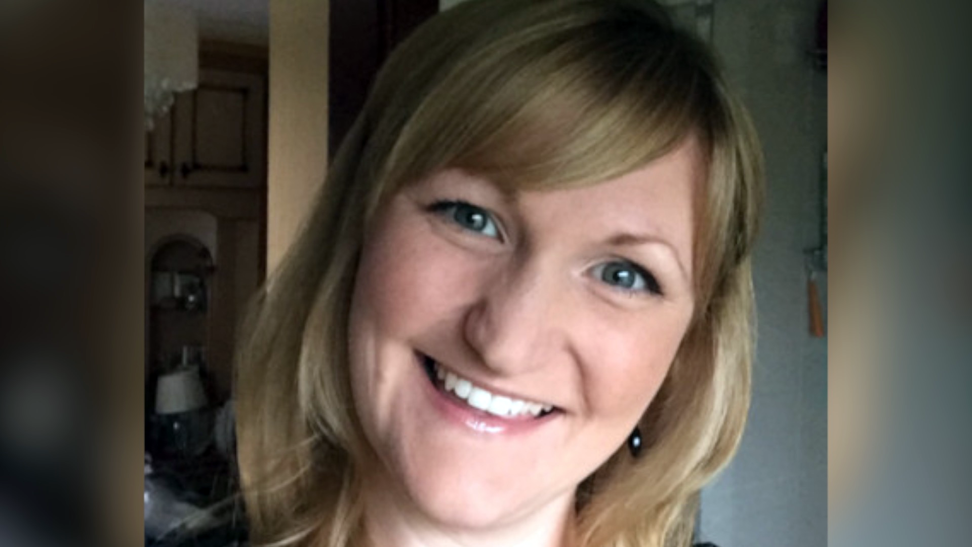 A photo of Karen Booth, smiling broadly with her head tilted. She has blonde hair with a sweeping fringe and the image is closely cropped showing her face and neck.  