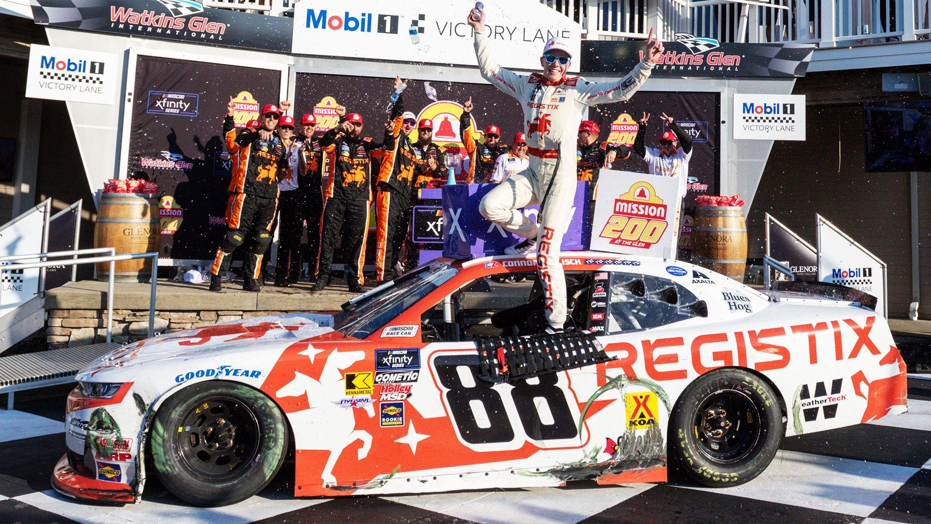 Conor Ziisch stands on top of his car door while he his celebrates his win