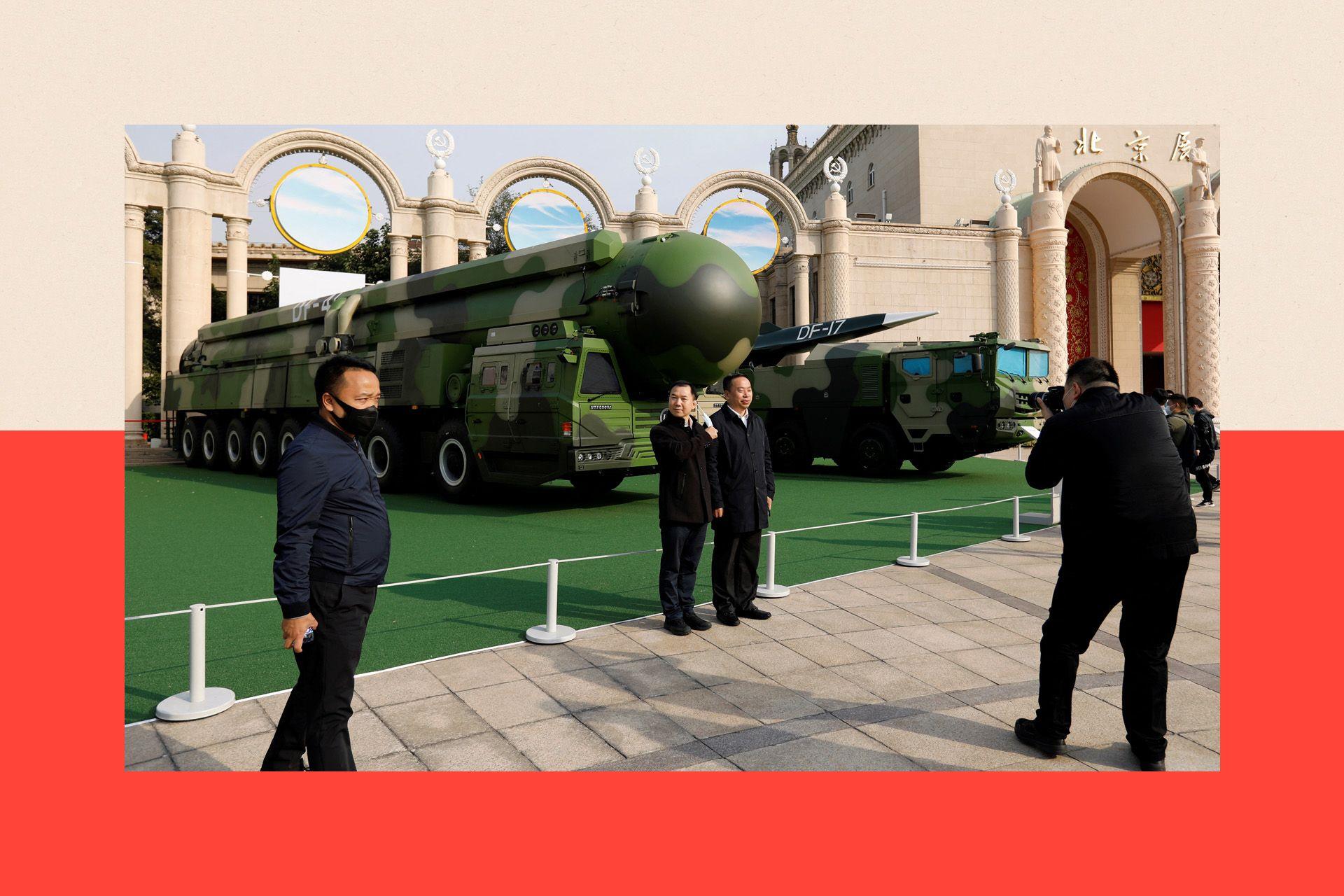 Visitors pose for pictures near displays of military vehicles carrying DF-41 intercontinental ballistic missile and DF-17 hypersonic missile at an exhibition