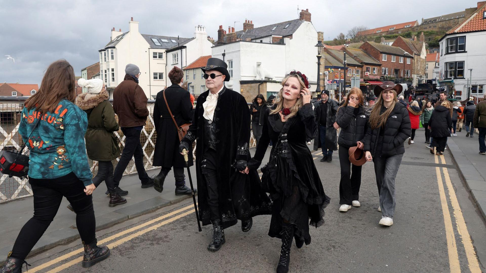 A couple wearing costumes walks through the town on Halloween during Whitby Goth Weekend in Whitby