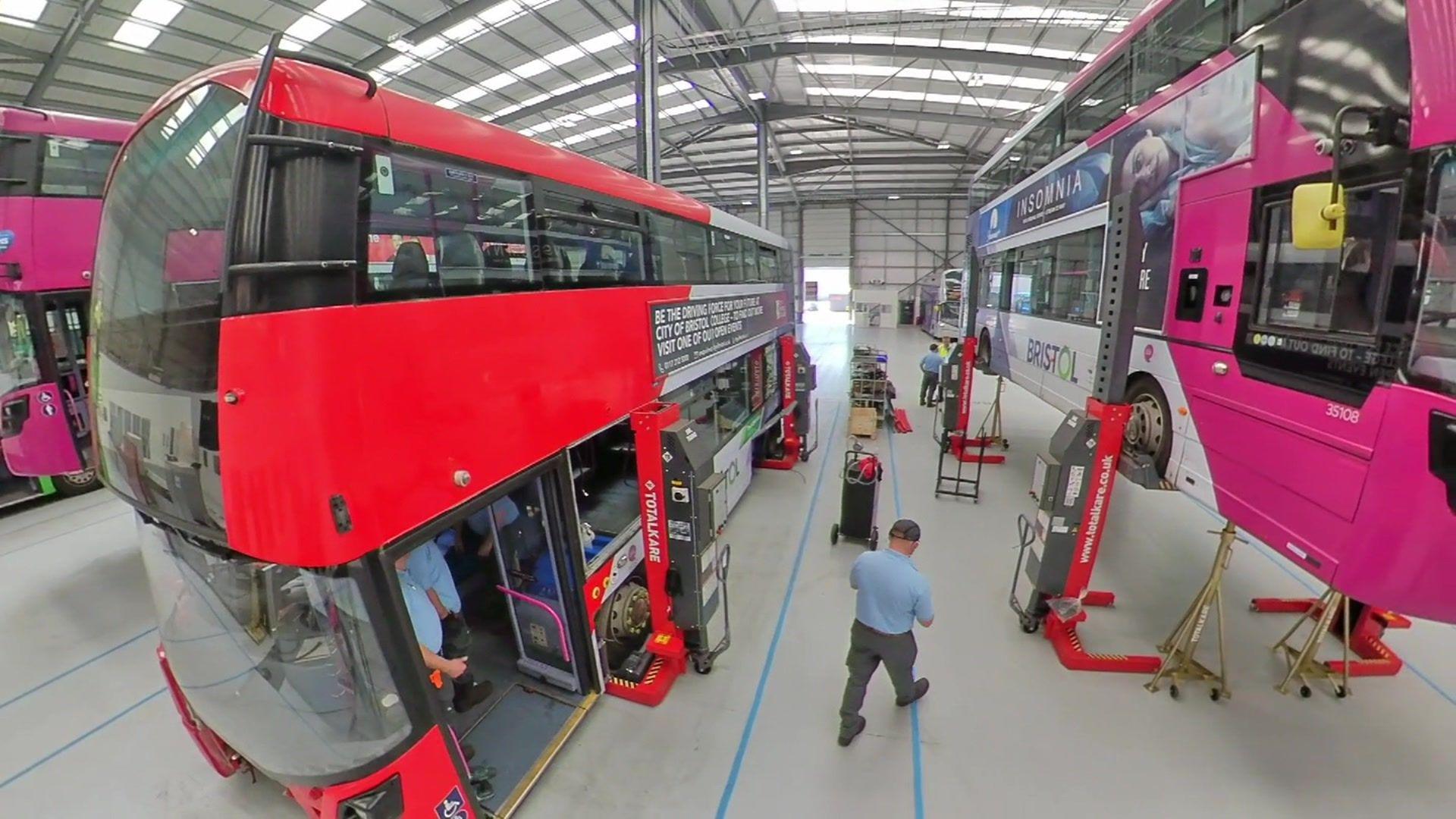 Buses of different colours inside a warehouse