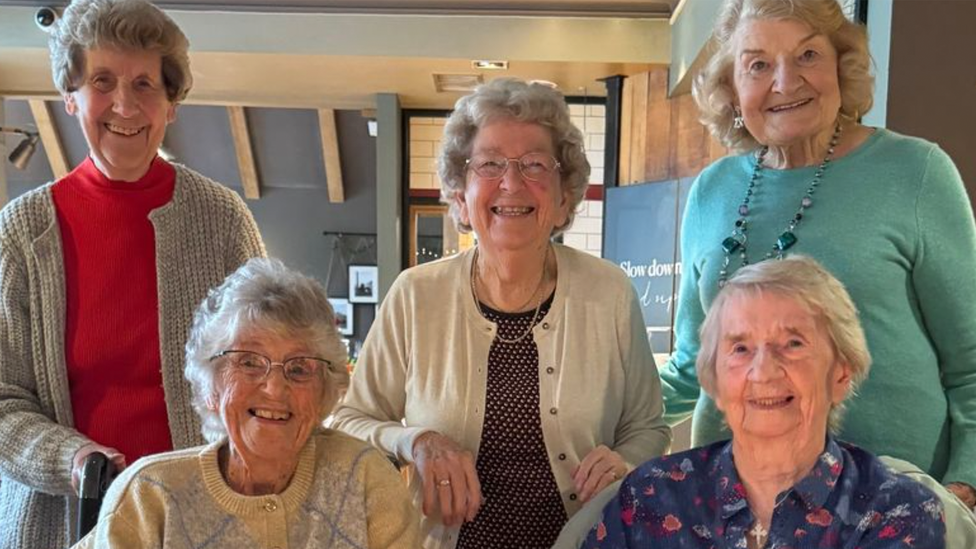 Five women pose for a photo during their school reunion.