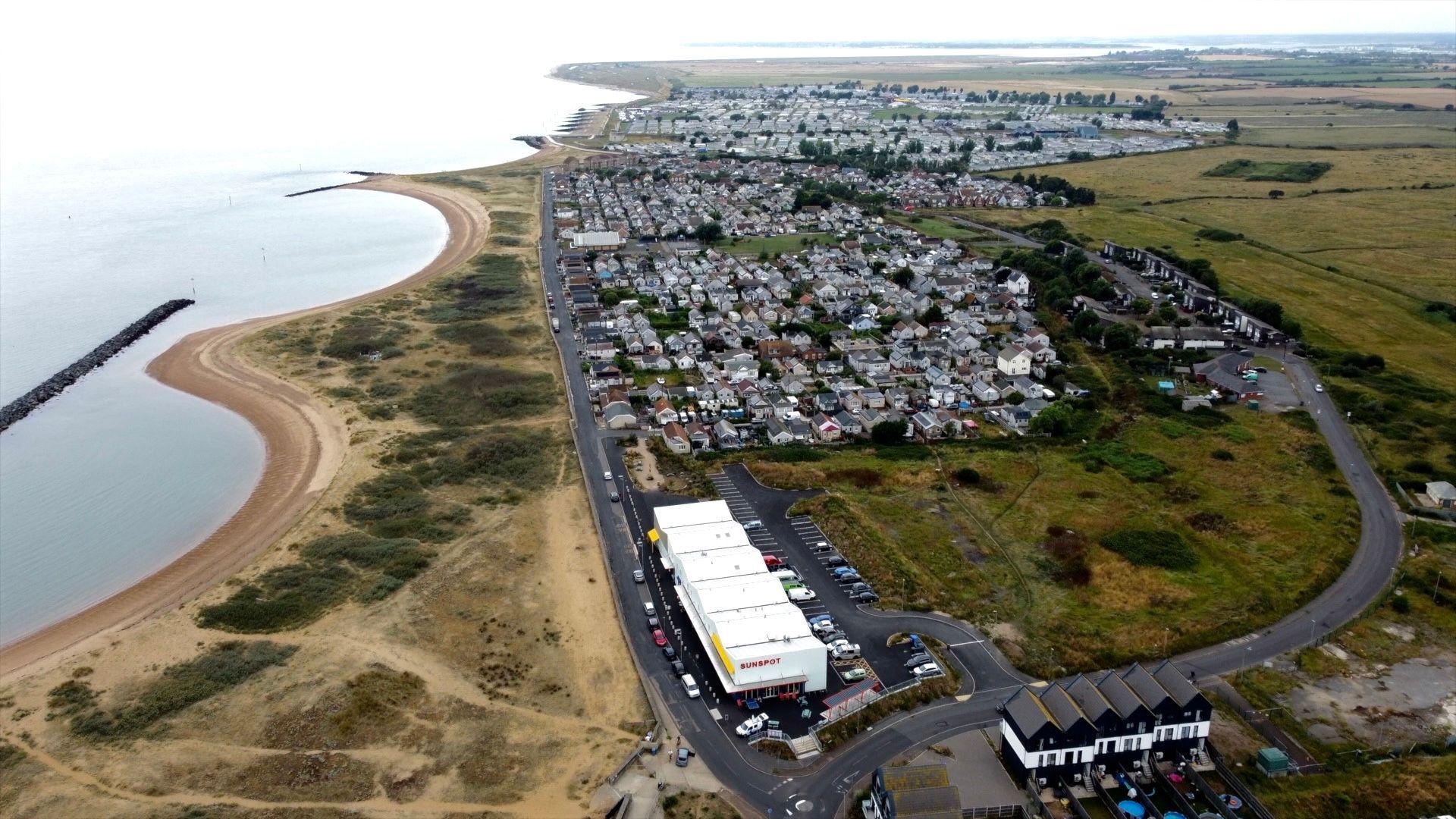 A bird's eye view of a seaside village with houses, the coast and the sea visible