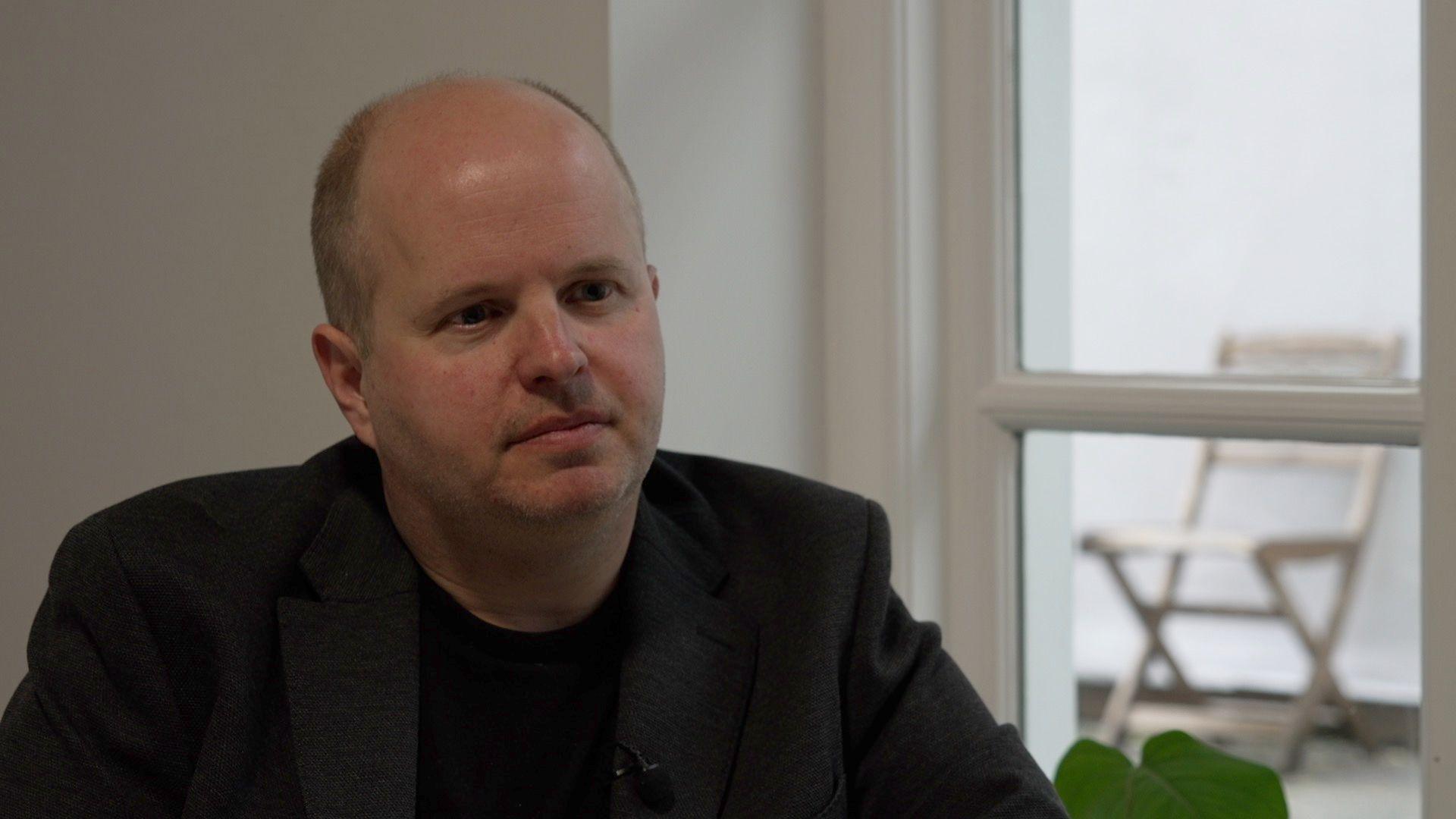 Jon Andrews in a black t-shirt and blazer.