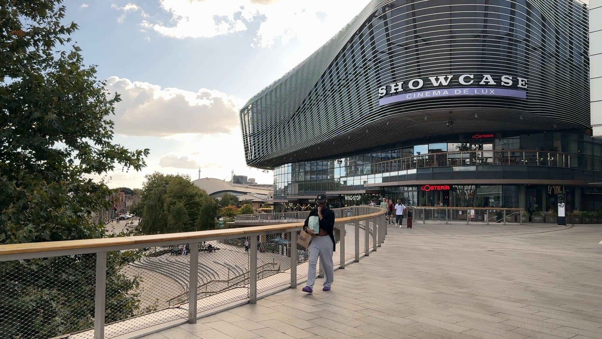 Showcase cinema in Westquay taken from the Portland Terrace entrance. There is a woman walking past the camera and the sky is sunny and blue with a few clouds.