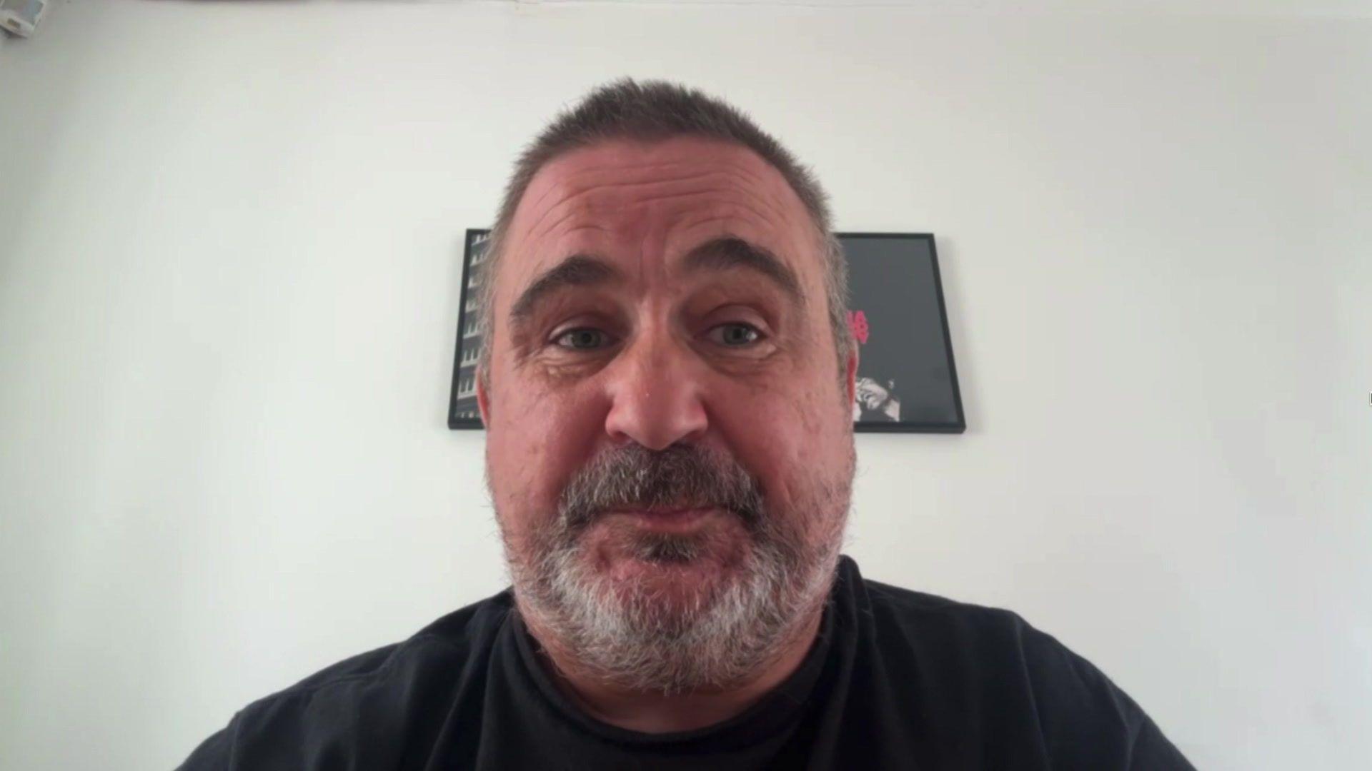 Head and shoulders picture of Andrew Smith who has a short grey beard and hair and is wearing a black t-shirt