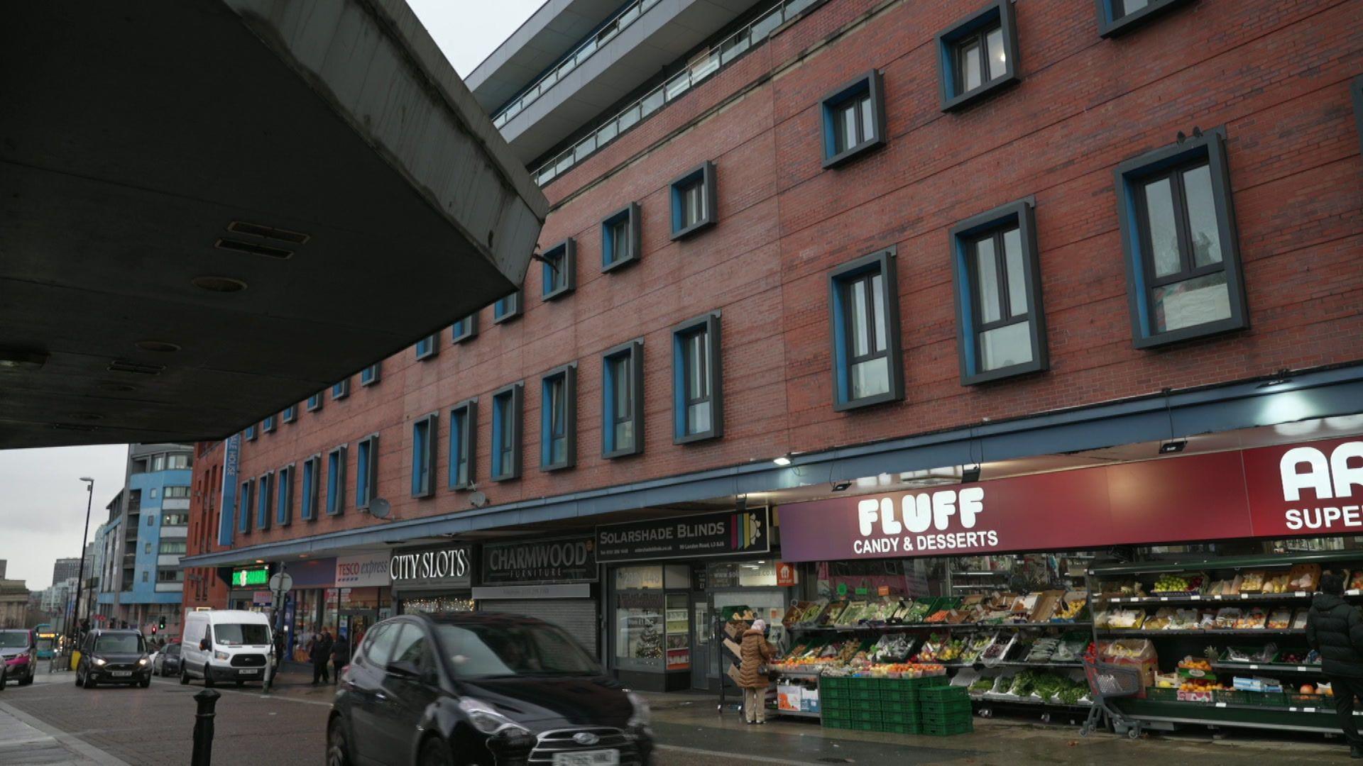 The exterior of the Arndale House student accommodation block in Liverpool. It is a seven-storey building with shops including a Tesco Express, a blinds shop and a Fluff candy and desserts store on the ground floor