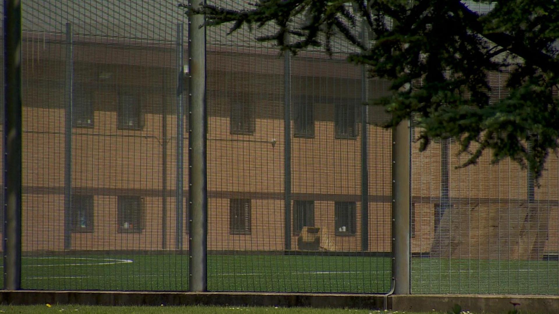 A view of a wing on HMP Hindley through the railings around an astro turf football pitch. 